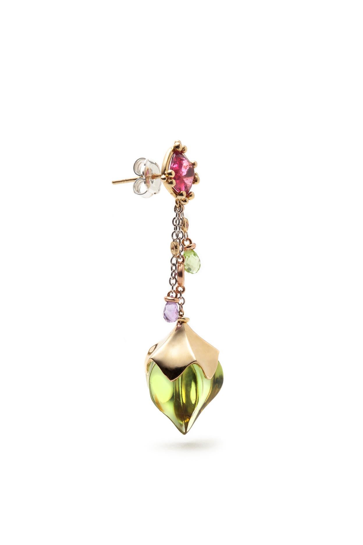 The ESTIVA earrings are made from 18K yellow, white and pink gold. Fancy cut green amber mounted in yellow gold flower cup settings hangs from cushion cut pink tourmalines. White gold chains adorned with amethyst and peridot briolettes; and faceted