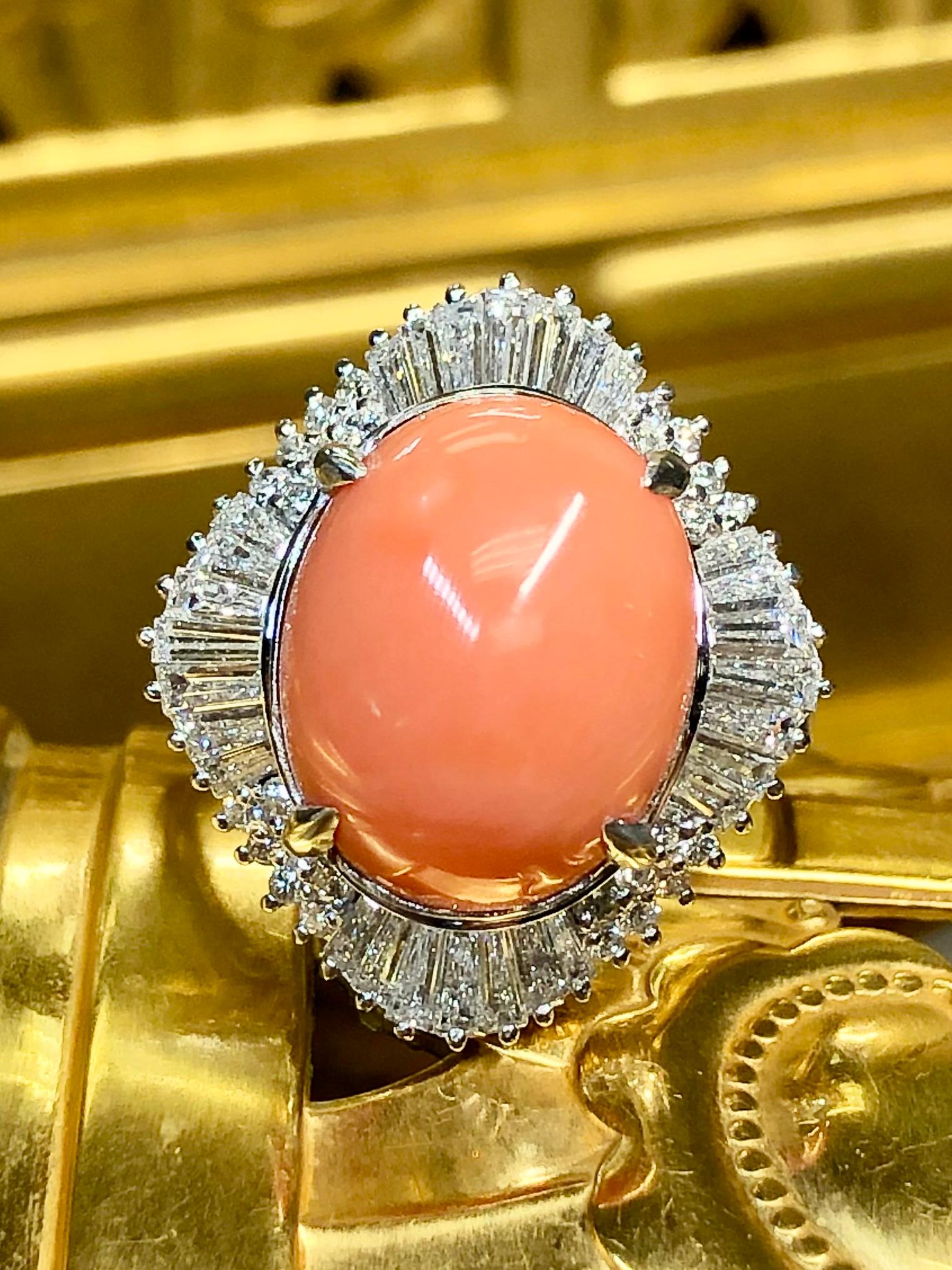 An elegant ballerina, ring, crafted in platinum and centered by a beautiful pink coral cabochon weighing 6.89ct (known weight) surrounded by approximately 1.80ctw in G-I color Vs1-2 clarity tapered baguette and round