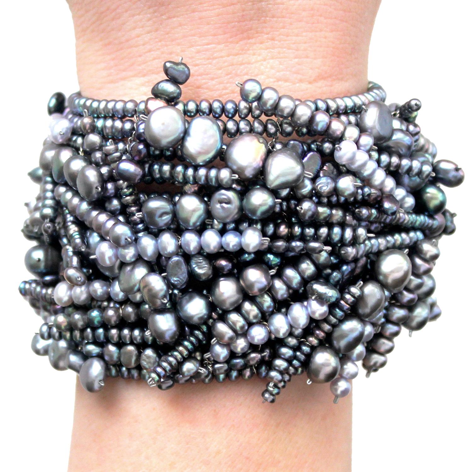 Chaos Cuff Bracelet handcrafted by jewelry artist Estyn Hulbert with thirteen rows of assorted blue and silver colored pearls strung on an yellow gold filled chain. Very flexible, and easily stretches to open and close comfortably around the wrist. 