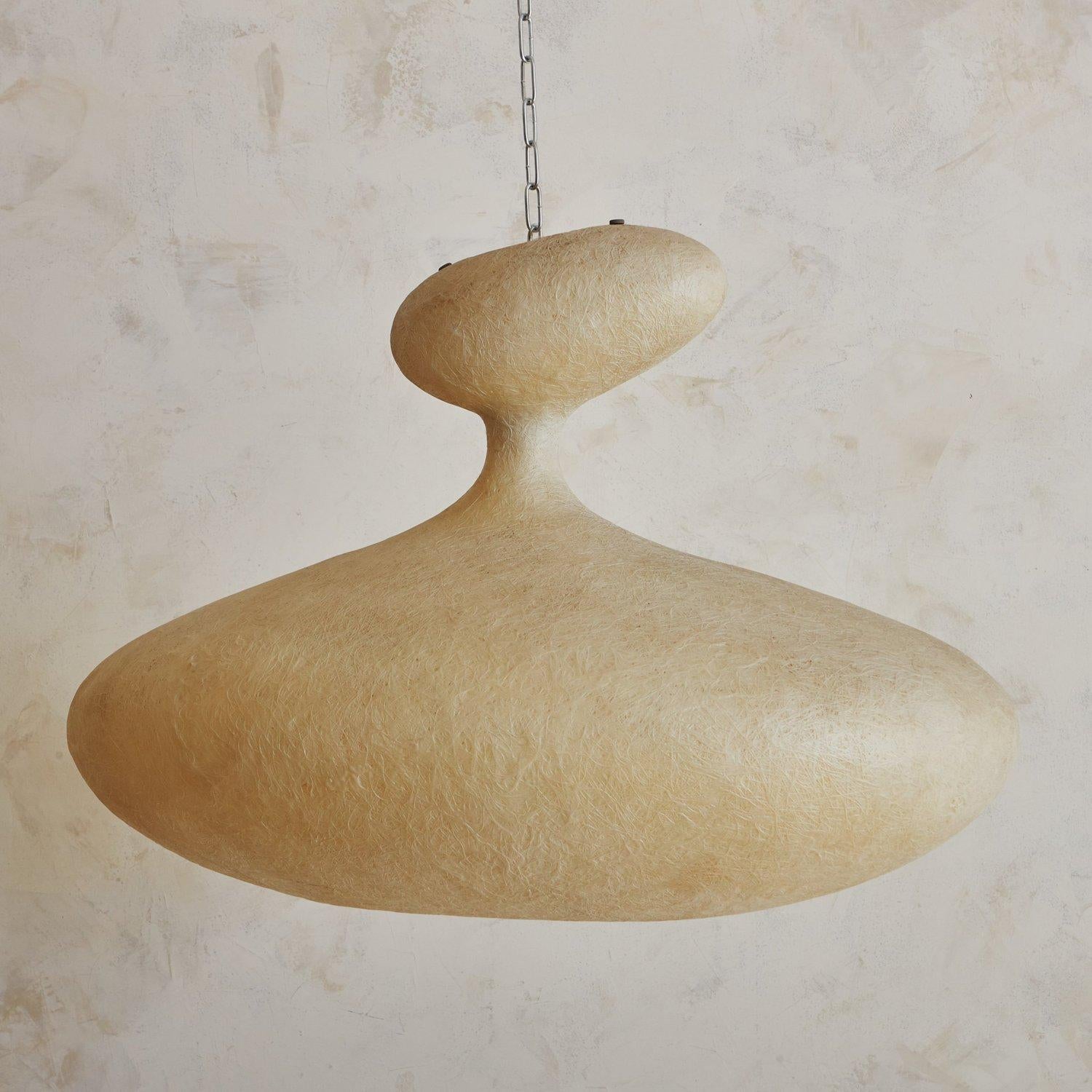 An Italian E.T.A. SAT pendant light designed by Guglielmo Berchicci for Kundalini in the 1970s. This striking piece features a fiberglass shade with soft, organic curves and an asymmetrical silhouette. It has a metallic frame, a polycarbonate