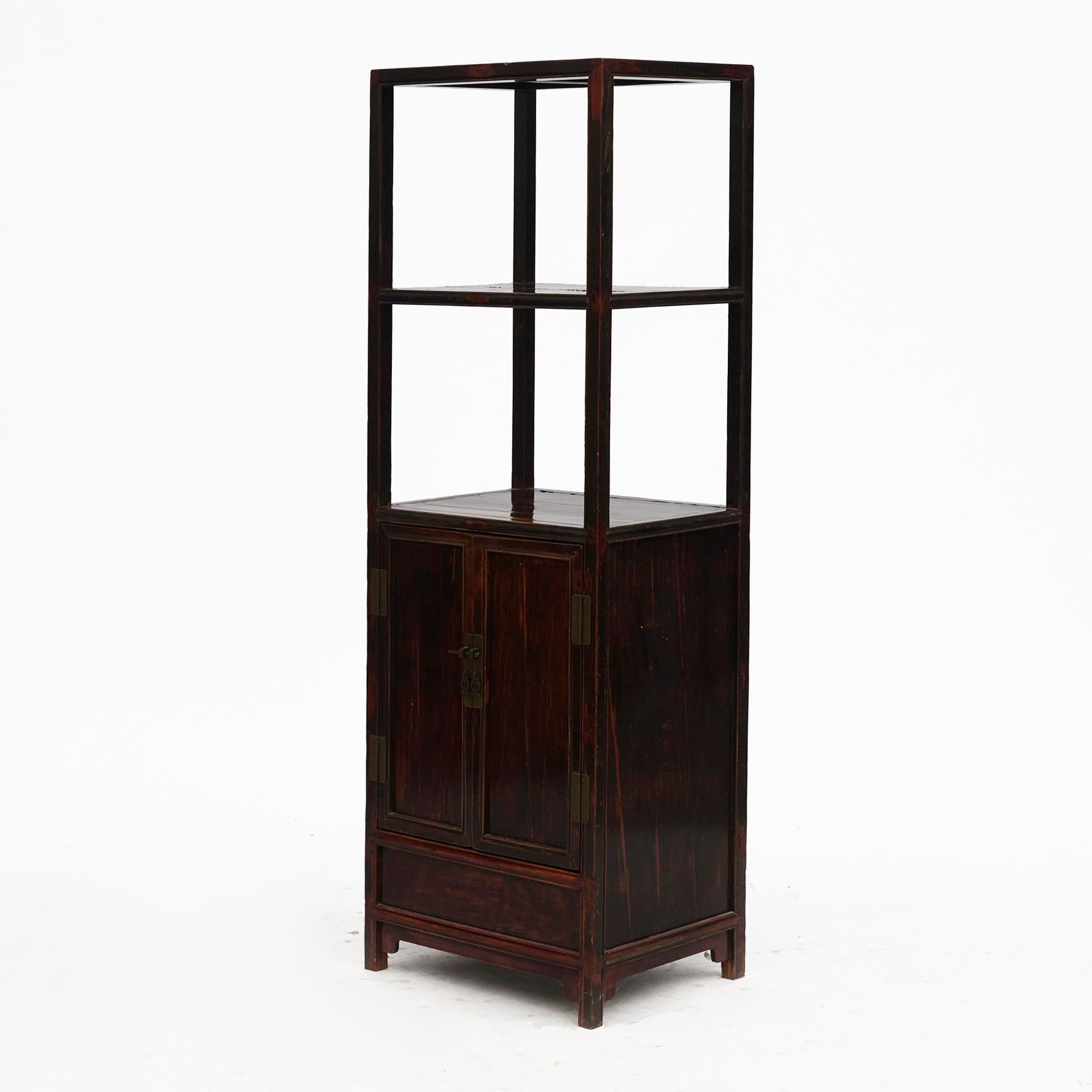 Elegant etagere cabinet in Ming style.
Made in walnut with burgundy lacquer finish
Frame with elegant profiles. Lower part has a double door with metal fittings.
Natural age-related patina.

From China, Jiangsu Province approx. 1840.