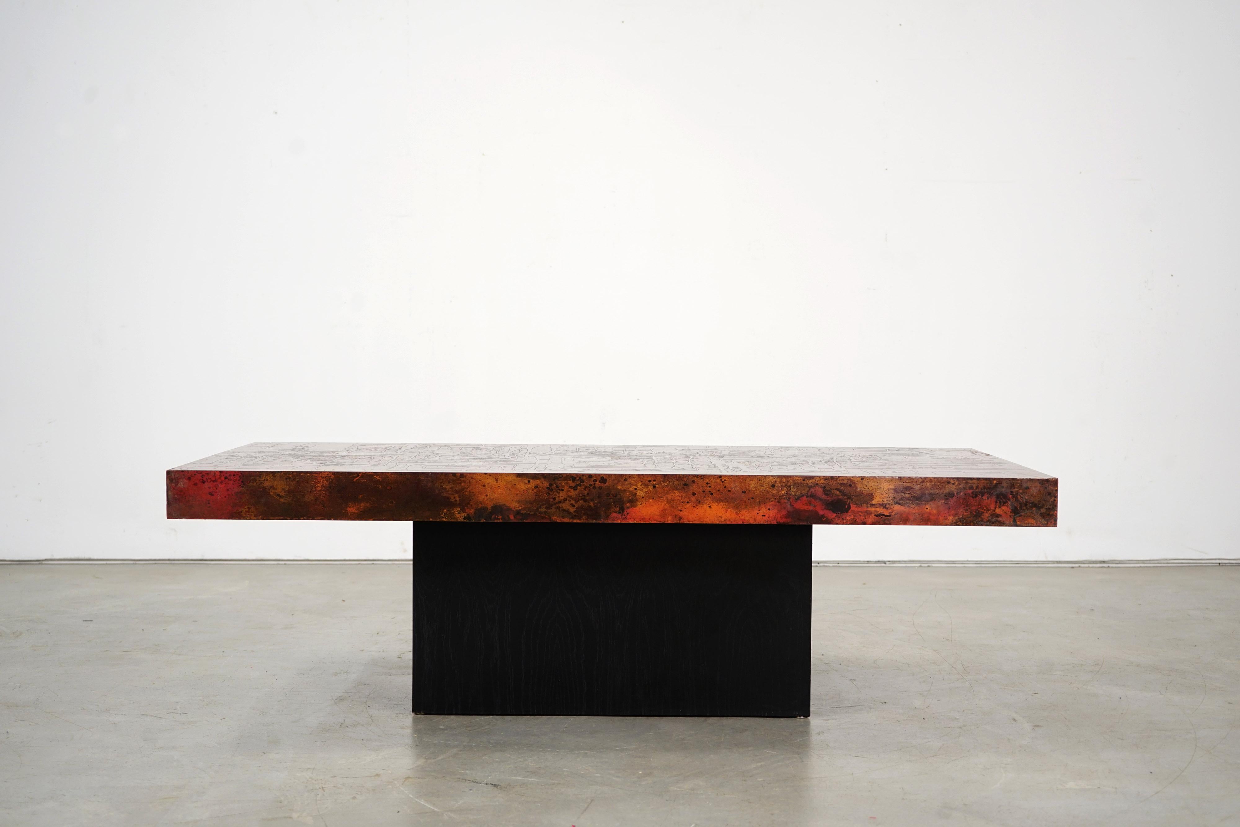 Beautifully oxidized copper tabletop resting on a lacquered wooden base.

 