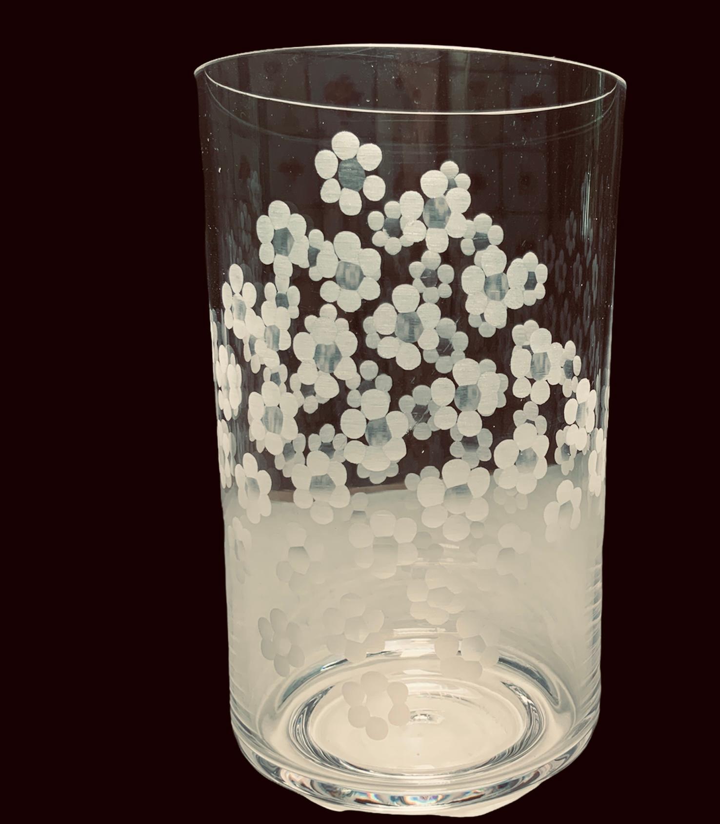 This is a clear crystal cylindrical shaped vase. It is decorated with multiple flowers etched in the center of it. Under the base is an acid etched signature-MR or MB with some numbers.