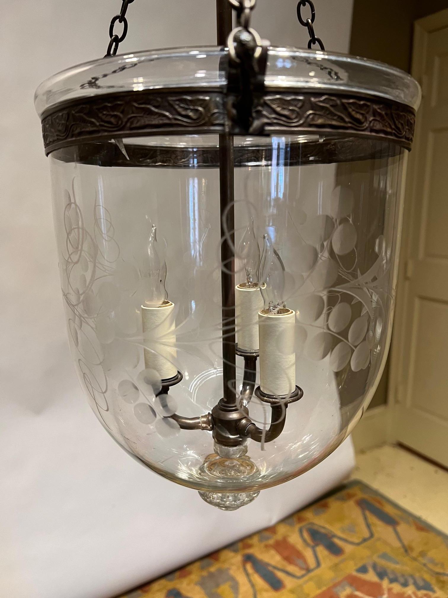 This hand blown and etched bell jar lantern is decorated with a design of vines, berries, and leaves. It has a glass pontil at the bottom. The fixture was first wired around 50 years ago;' it was originally made to be a candle fixture. The hardware