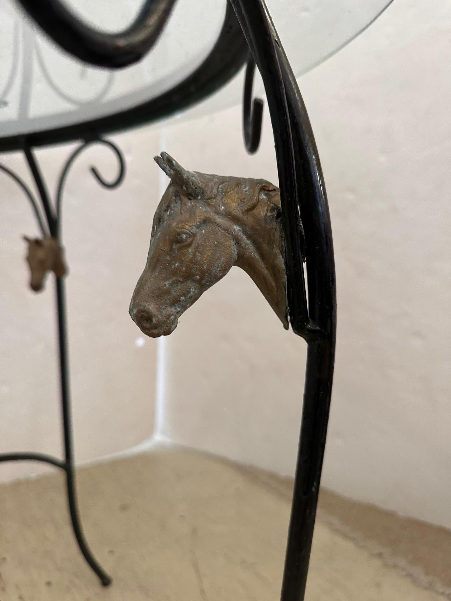 Table ronde en verre gravé à motif équestre, avec cheval et cavalier sur le plateau en verre, et têtes de cheval décoratives en fer ornant la base en fer.
Quelques rayures sur le verre, usure due à l'âge.

