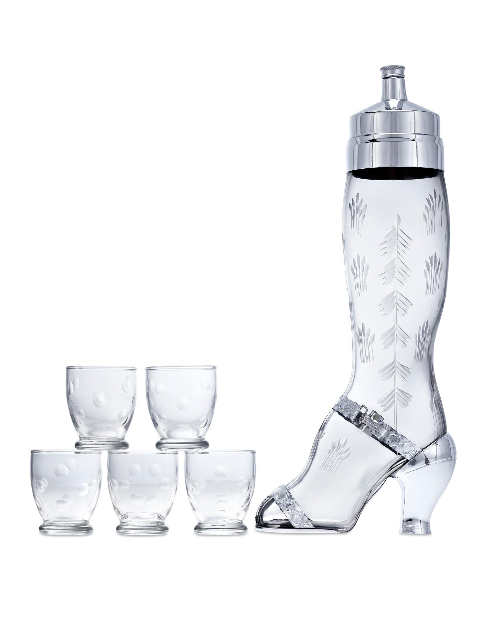 The form of a lady's leg entices one to imbibe with this etched glass cocktail set known as the “Shake a Leg” shaker. Made by the West Virginia Specialty Glass Co. with silverplate parts by Derby Shelton Silver Co. of Connecticut, the shaker is