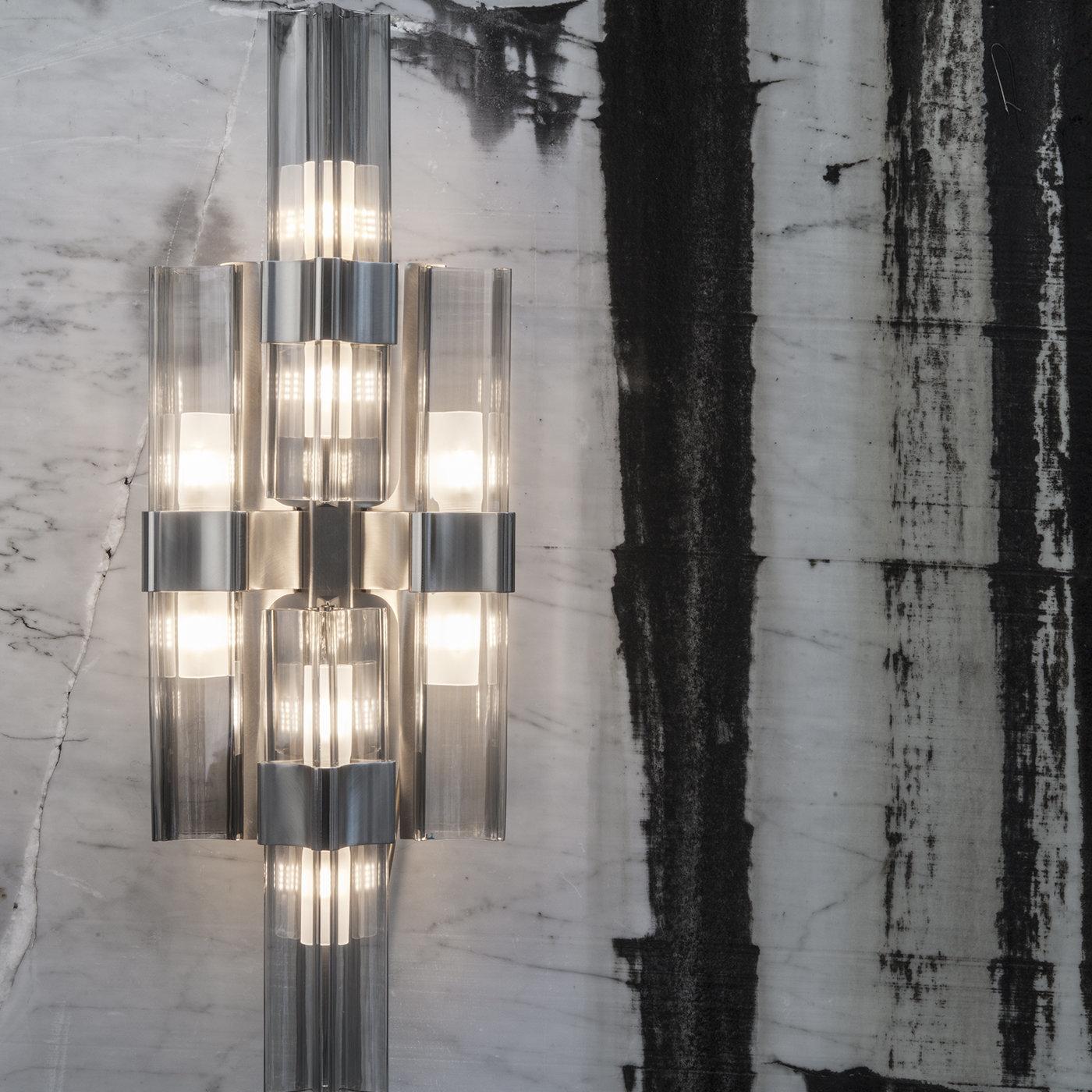 Fancy up the walls with some contemporary lighting with this wall lamp, part of the Eterea collection, that will light up any space. The lamp’s transparent crystal shades with smoke gray accents are arranged in a simple, geometrical form. A perfect