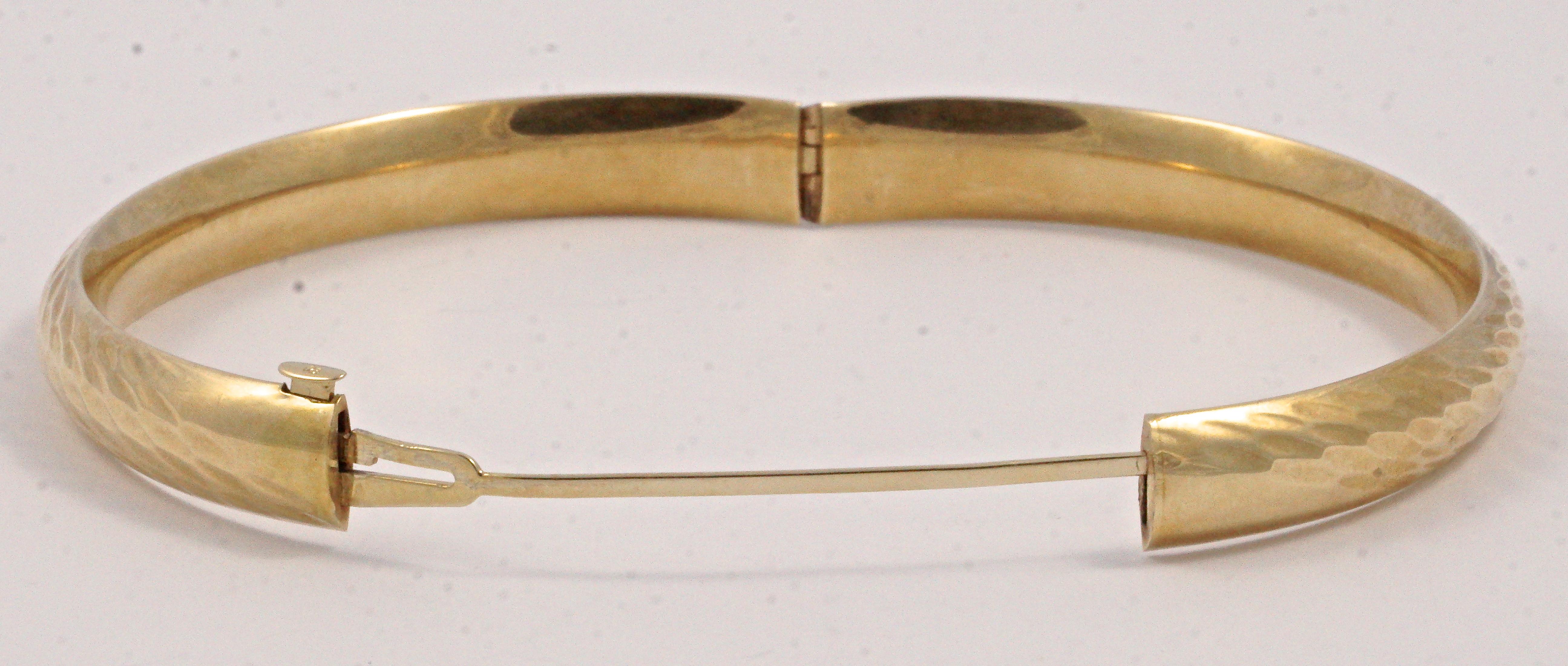EternaGold 14K gold Costa Rica bangle, featuring a ripple design. The bangle is hollow and light to wear, and is slightly oval measuring 6.5cm / 2.56 inches by 6cm / 2.36 inches diameter, the width is 8mm. / .31 inch. It opens with a push button and