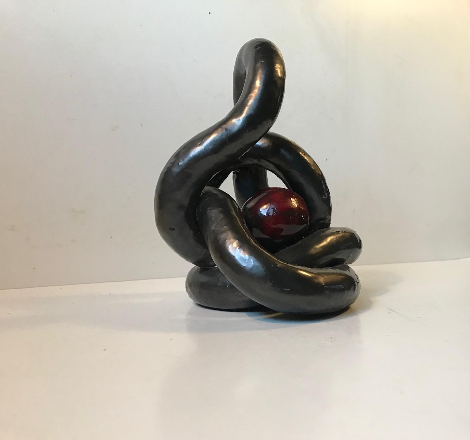 An ornamental play on the Classic eternity symbol. This modernist sculpture by an anonymous Danish ceramist would serve as a fine focal point in any living room setting. It is executed in clay and applied with a black almost lustre-like main glaze.