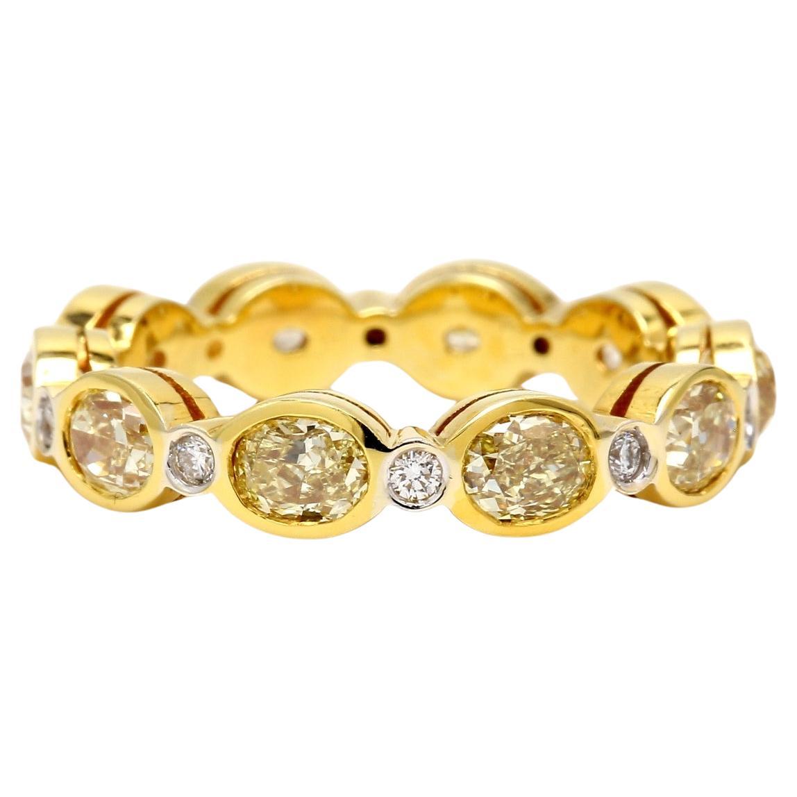 Anillo de eternidad en 18K YG con diamantes redondos y ovalados amarillo fantasía. D3.29ct.t.w.