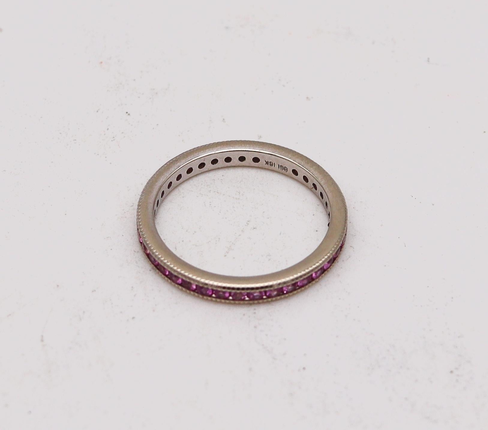 An eternity ring band with natural pink sapphires.

Contemporary eternity band ring crafted in America in solid white gold of 18 karats with high polished finish. It is mounted in a plain channel setting with 38 calibrated round brilliant cuts of