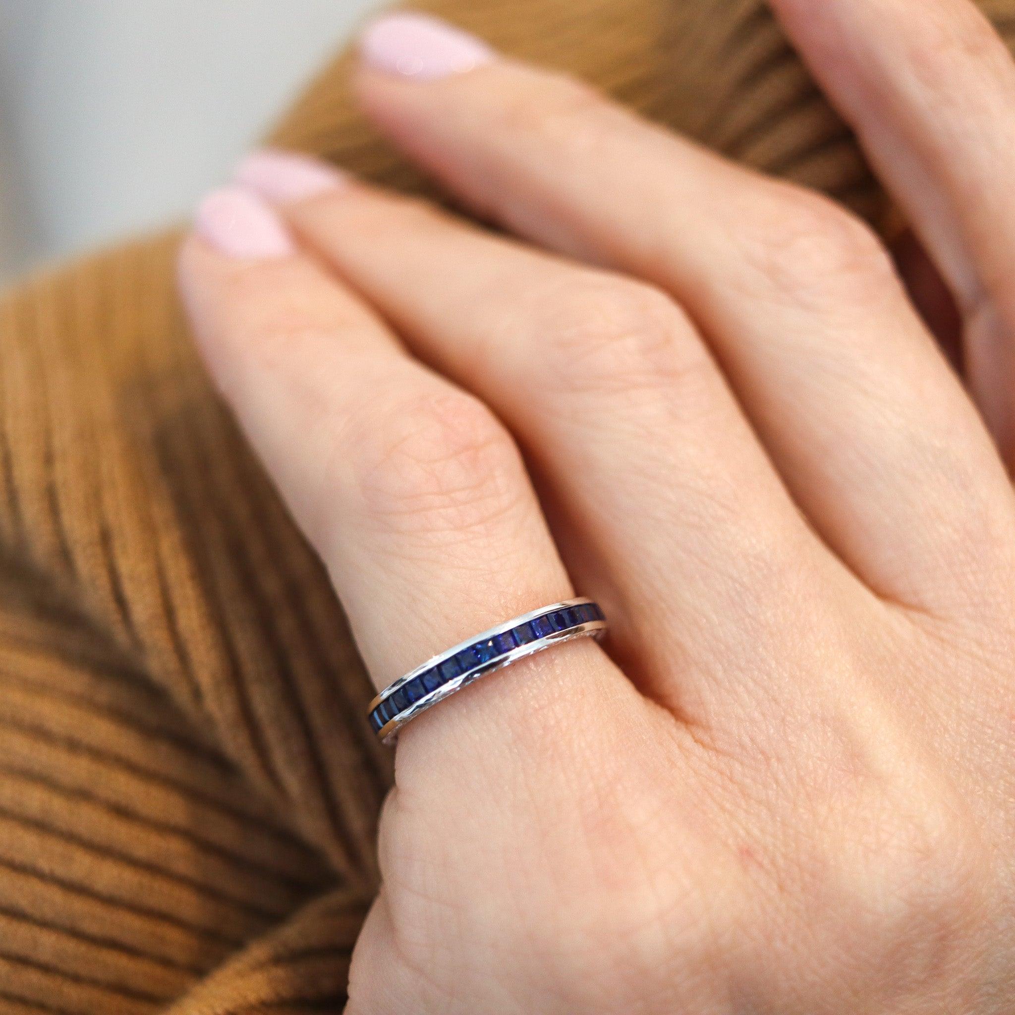 Eternity channel ring with natural blue sapphires.

This is a modern full eternity band carefully crafted in solid white gold of 14 karats with high polished finish. Both sides are decorated with floriated designs and is mounted in a continuous