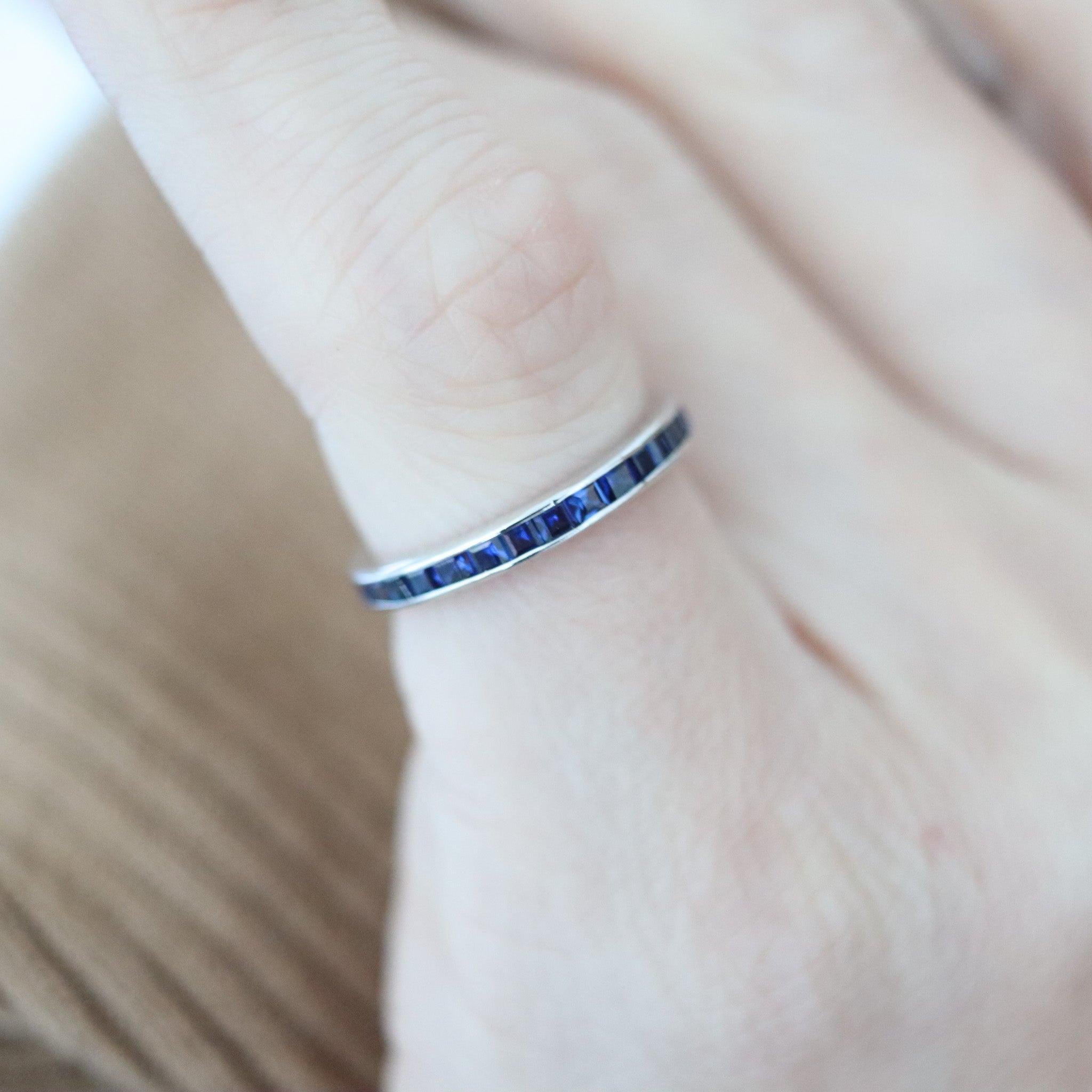 Un anello di eternità con zaffiri blu reali.

Si tratta di una classica e moderna fascia a eternità piena realizzata con cura in oro bianco massiccio a 14 carati con finitura lucida. L'anello ha un design semplice ai lati ed è impreziosito da