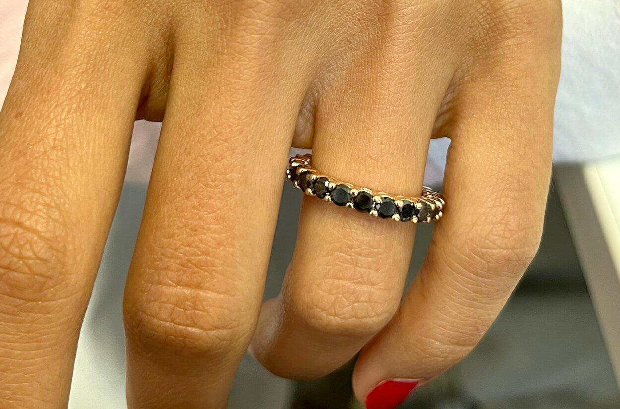 A captivating 18kt rose gold eternity ring, graced by the allure of natural black diamonds, creating a romantic and enchanting symbol of everlasting love, where the warm blush of rose gold and the mystique of black diamonds unite in timeless