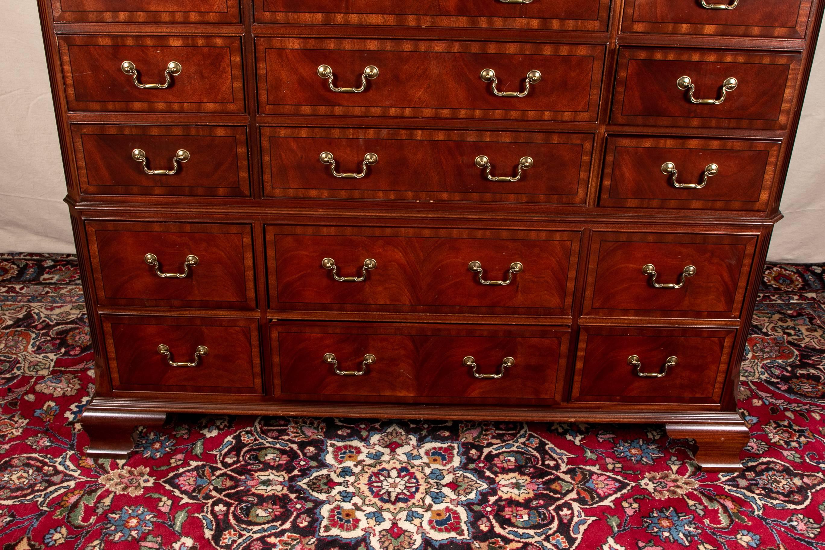Ethan Allen 18th century style mule chest, mahogany, carved cornice over a cabinet with fluted canted corners with acanthus leaf tops, top cabinet with three banks of banded drawers- four short flank four long ones, the lower cabinet with two banded