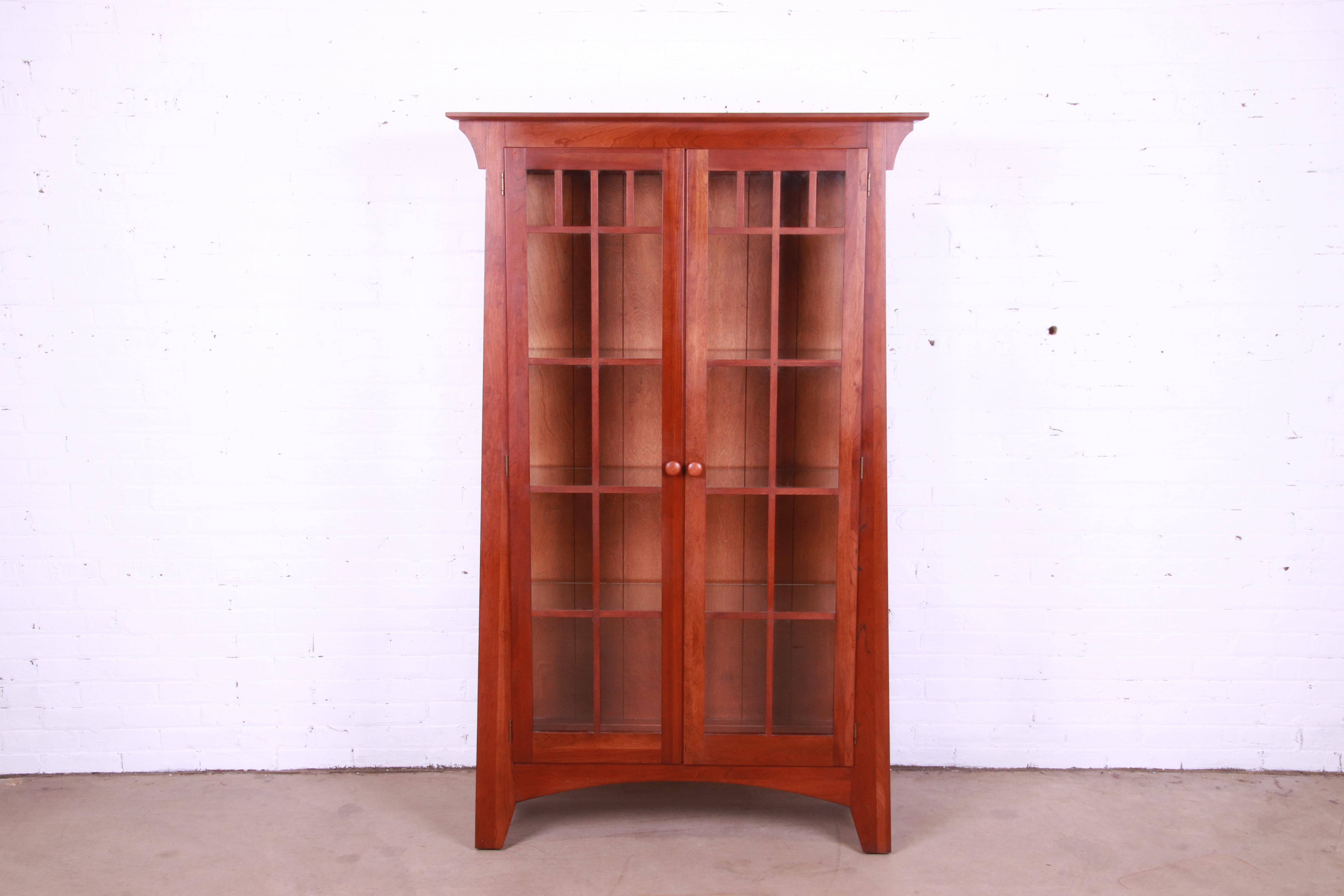 A gorgeous Mission or Arts & Crafts style lighted display cabinet or bookcase

In the manner of Gustav Stickley or Harvey Ellis

By Ethan Allen

USA, Circa 1990s

Solid cherry wood, with mullioned glass front and sides.

Measures: 43