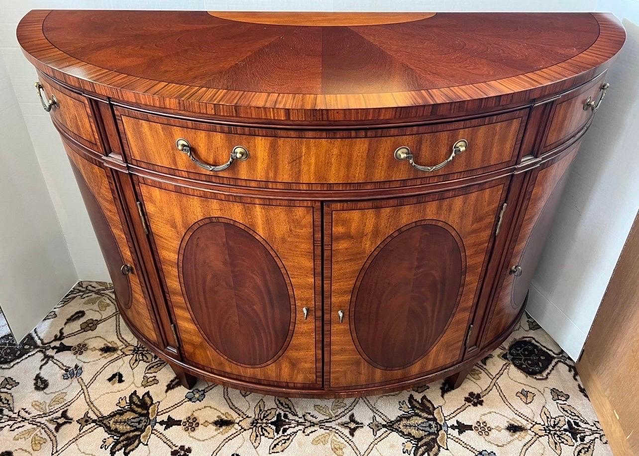 Classic Ethan Allen curved demilune credenza sideboard having mahogany and satinwood inlaid veneers with center drawer flanked by triangular drawers over bow front cabinet doors. In excellent condition.