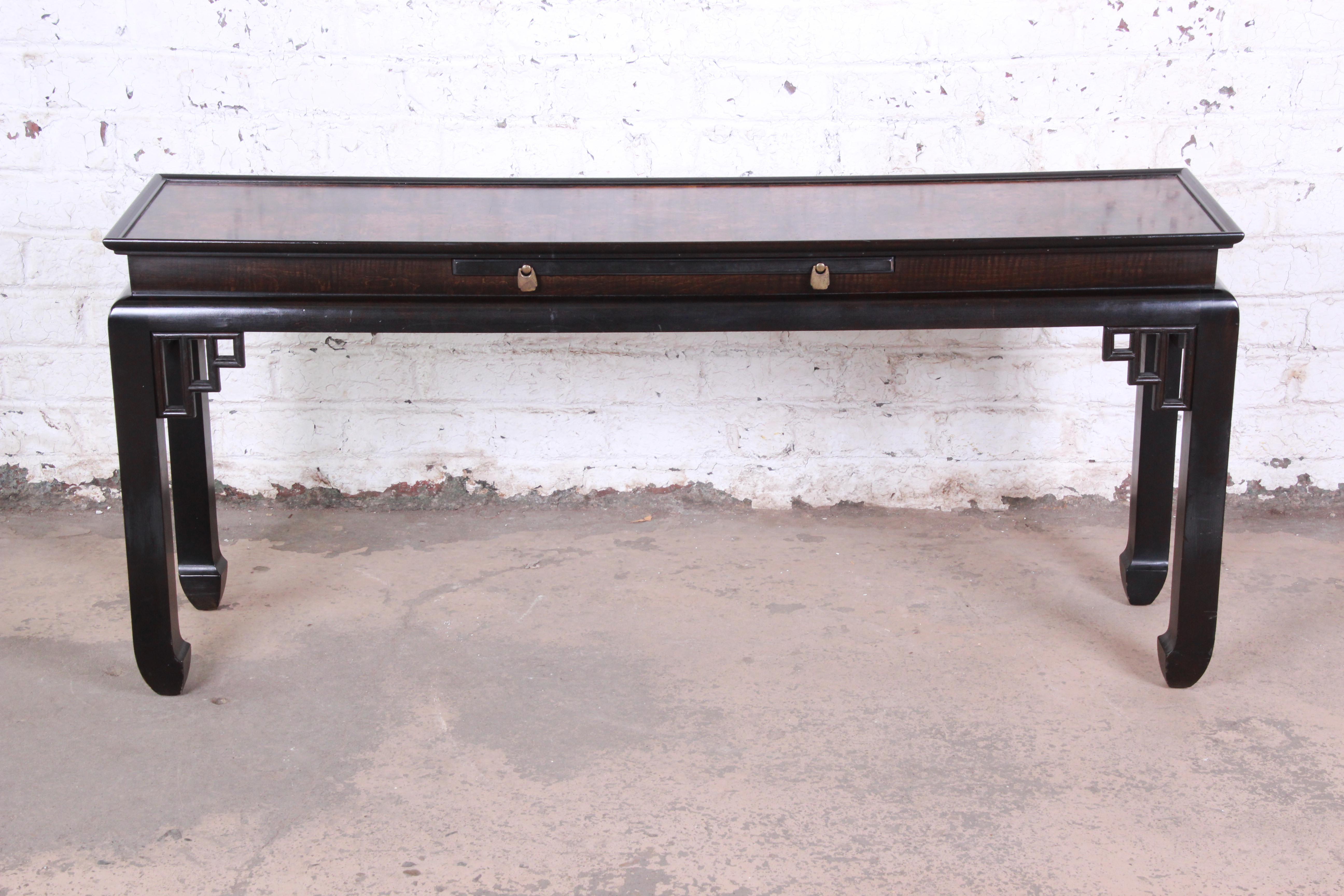 A gorgeous Hollywood Regency Chinoiserie console table by Ethan Allen. The table features beautiful carved Asian details, a nice black lacquered finish, and a stunning burl wood top. It has a single pull-out writing slab with original brass