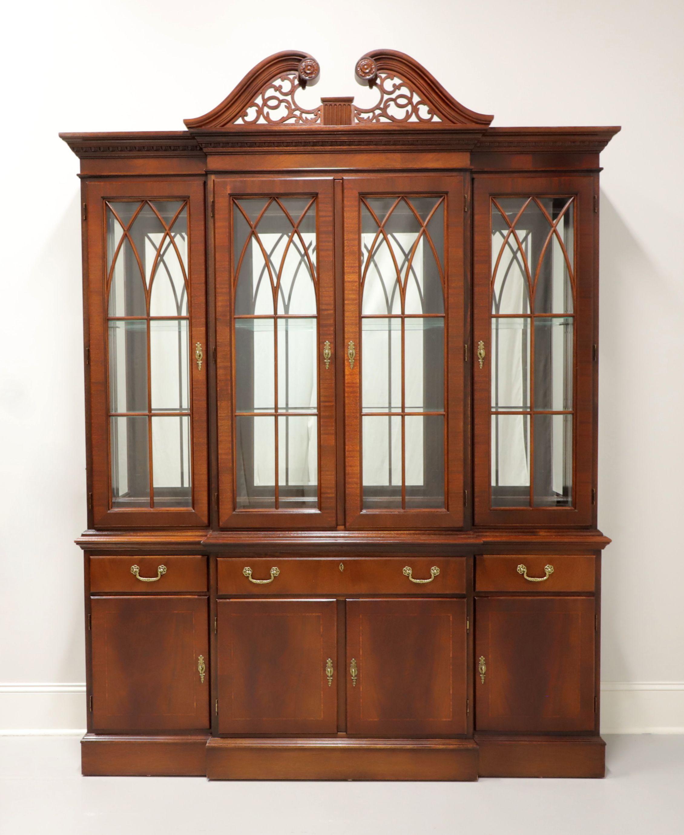 A Chippendale style breakfront china cabinet by Ethan Allen, from their 18th Century Collection. Mahogany with inlays and brass hardware. Upper cabinet features three lighted compartments with two adjustable plate-grooved glass shelves in each, four