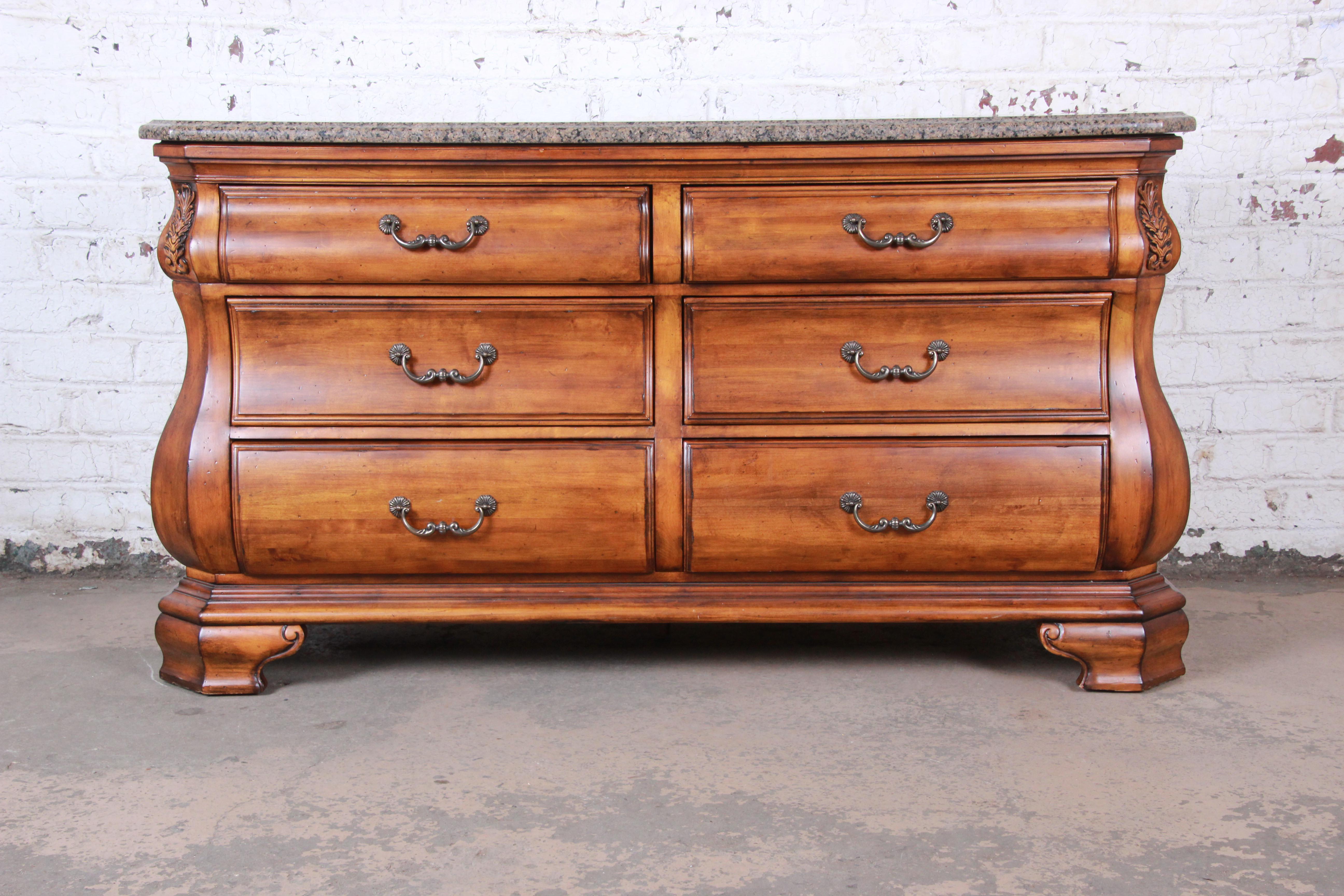 An exceptional Italian style carved wood dresser or credenza by Ethan Allen. The dresser features gorgeous wood grain with nice carved details and a stunning beveled granite top. It is very well made, with solid wood construction and dovetail