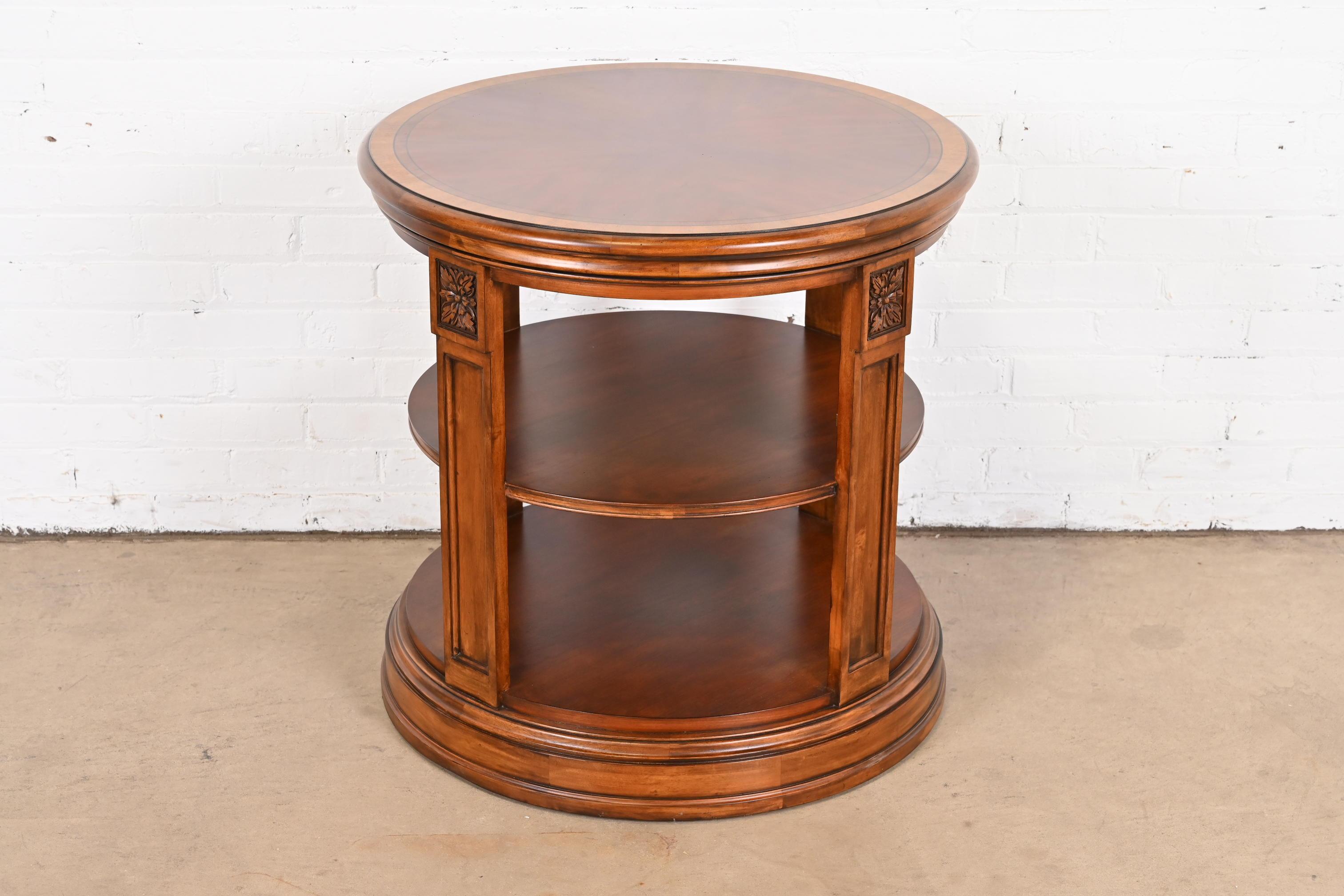 A gorgeous Regency style three-tier drum side table

USA, Late 20th Century

Carved mahogany, with satinwood banding.

Measures: 28