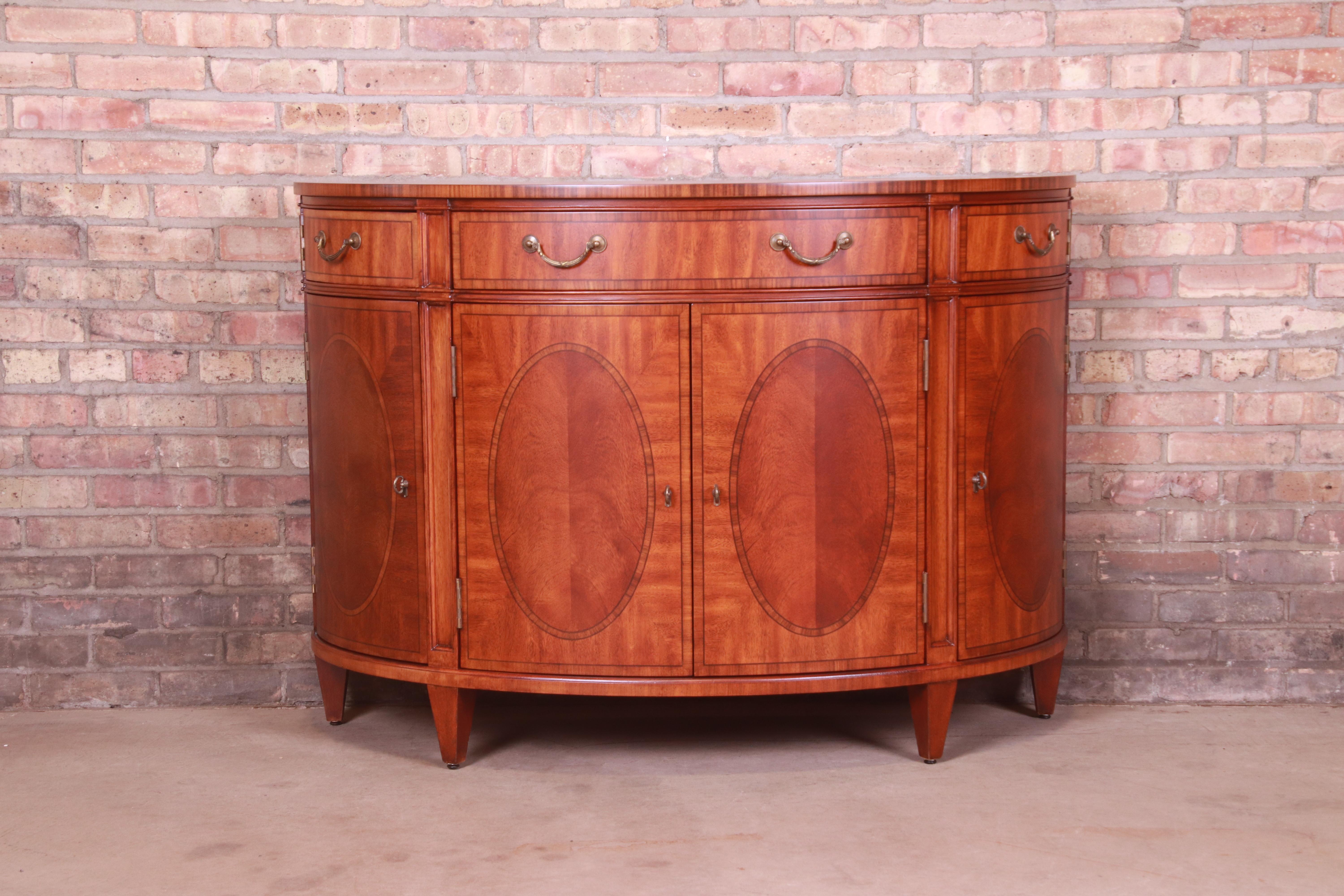 A gorgeous Regency style demilune sideboard, console, or bar cabinet

By Ethan Allen

USA, Circa 1990s

Inlaid mahogany and satinwood, with original brass hardware.

Measures: 50