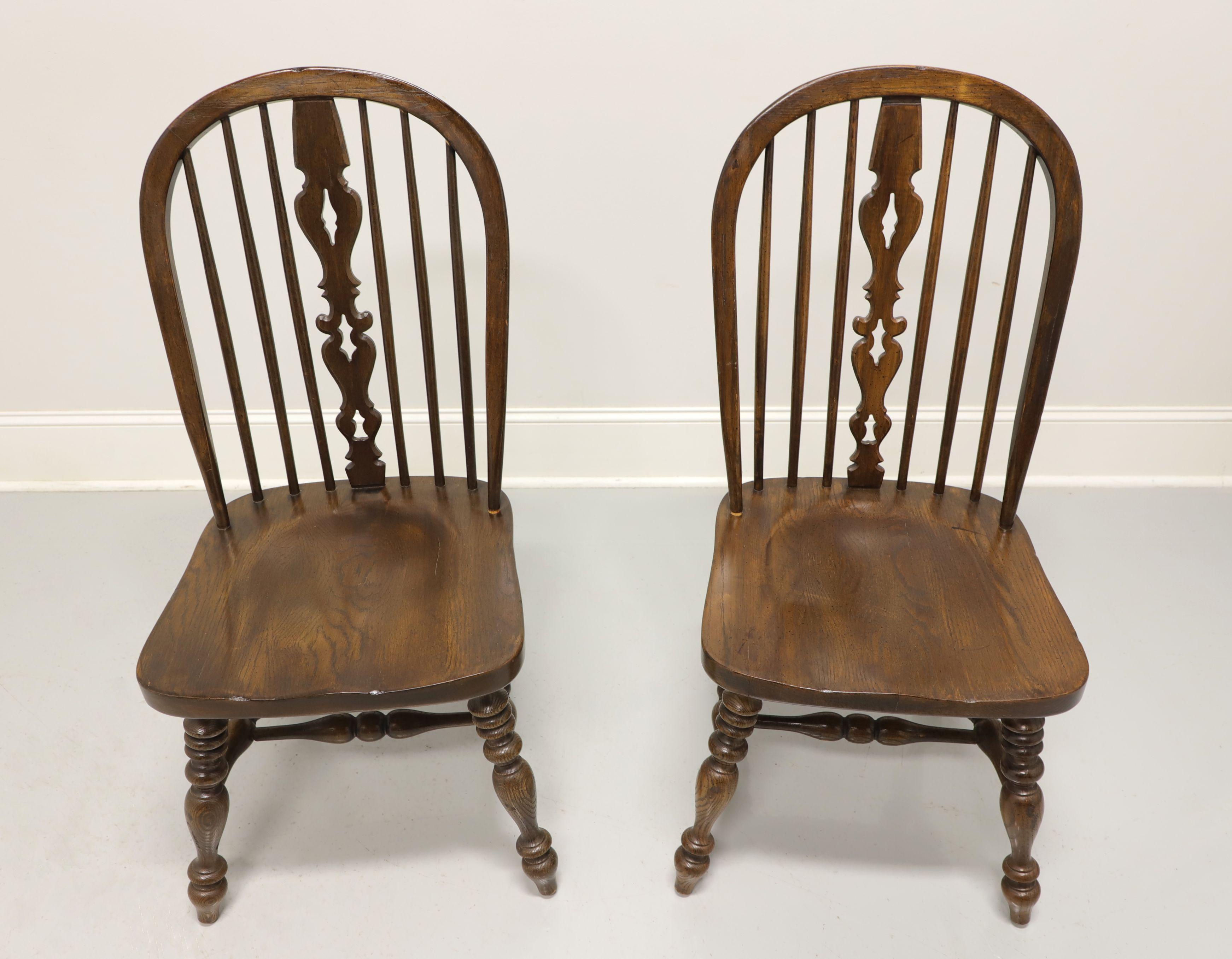 A pair of Windsor style dining side chairs by Ethan Allen, from their Royal Charter collection. Solid oak with bowback, spindle back with carved center backsplat, turned legs and stretchers. Made in the USA, in the late 20th century. 

Measures: