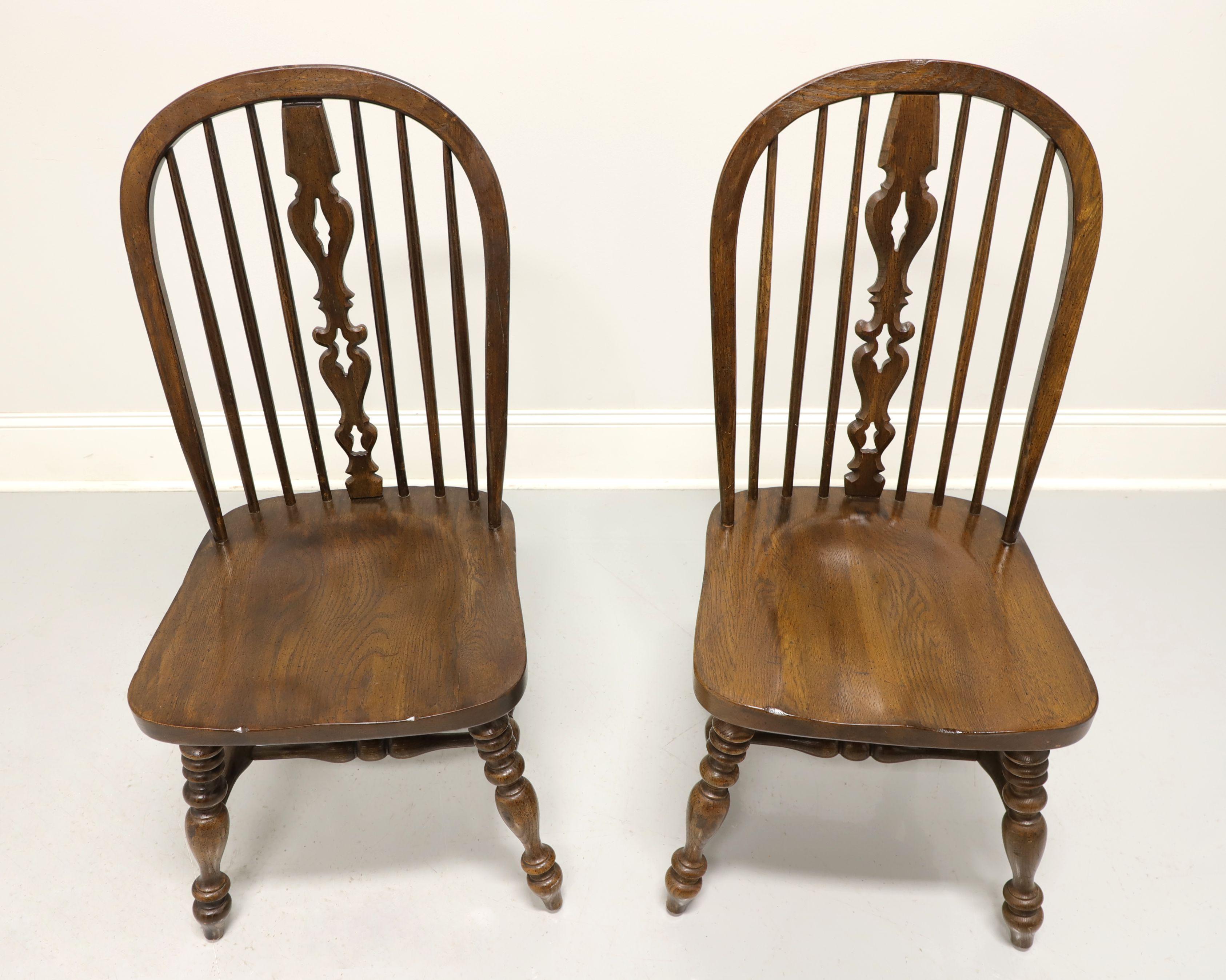 A pair of Windsor style dining side chairs by Ethan Allen, from their Royal Charter collection. Solid oak with bowback, spindle back with carved center backsplat, turned legs and stretchers. Made in the USA, in the late 20th century. 

Measures: