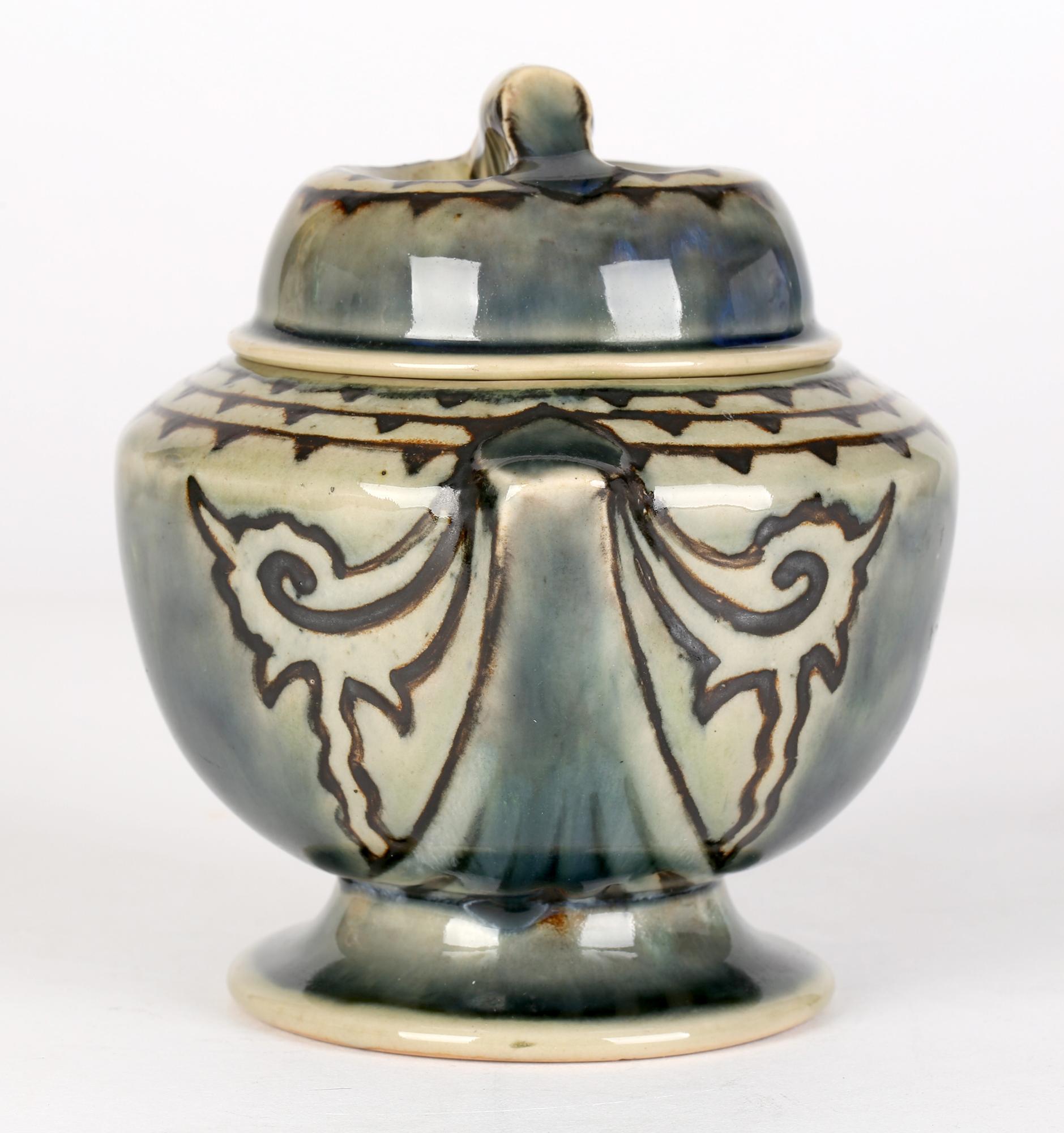 An unusual Doulton Lambeth Art Deco stoneware tobacco jar and cover decorated with patterned designs by Ethel Beard and Joan Honey and dated 1925. The jar has the feel of heavy porcelain with the round bodied jar raised on a pedestal foot with