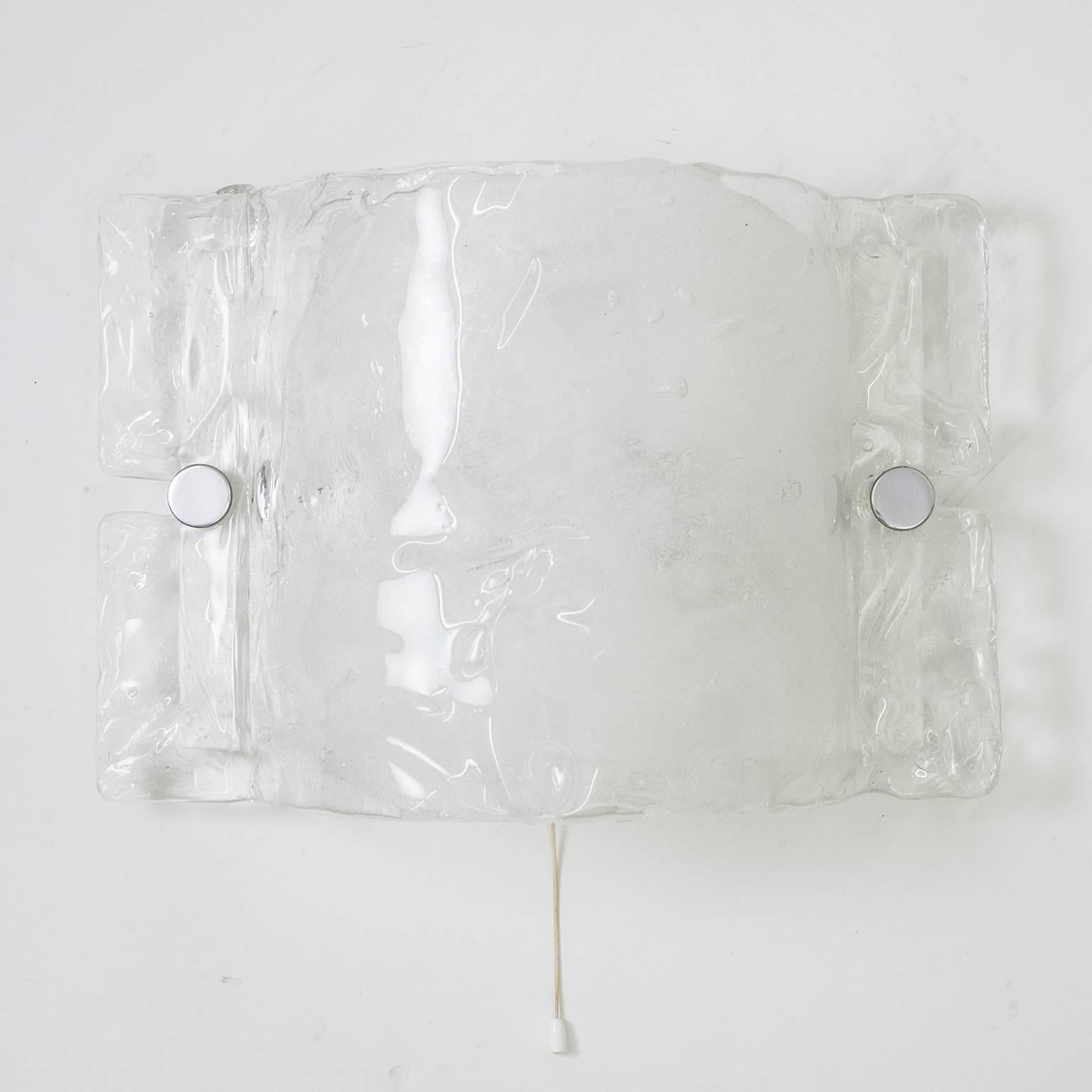 Very ethereal 1970s Kalmar wall light. It's got a white lacquered backplate and a large heavily textured and curved diffuser made of transparent glass with large brush strokes of tiny bubbles in the centre covering the two original E14 sockets.