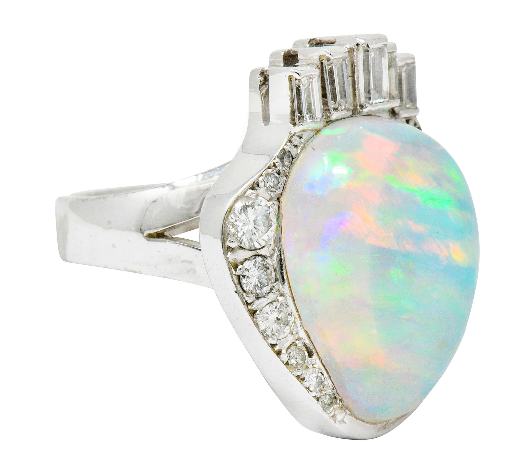 Centering a pear shaped jelly opal cabochon featuring spectral play-of-color

With abstract baguette and round brilliant cut diamond surround weighing approximately 0.75 carats total; G to J color with VS to I clarity

Overall ring is designed as a