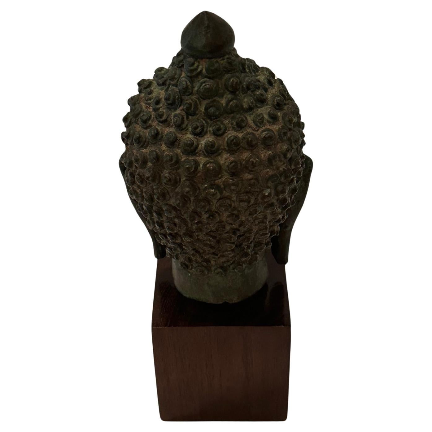 Lovely small Thai Buddha head sculpture in bronze with beautiful patina and mounted on a wooden cube.