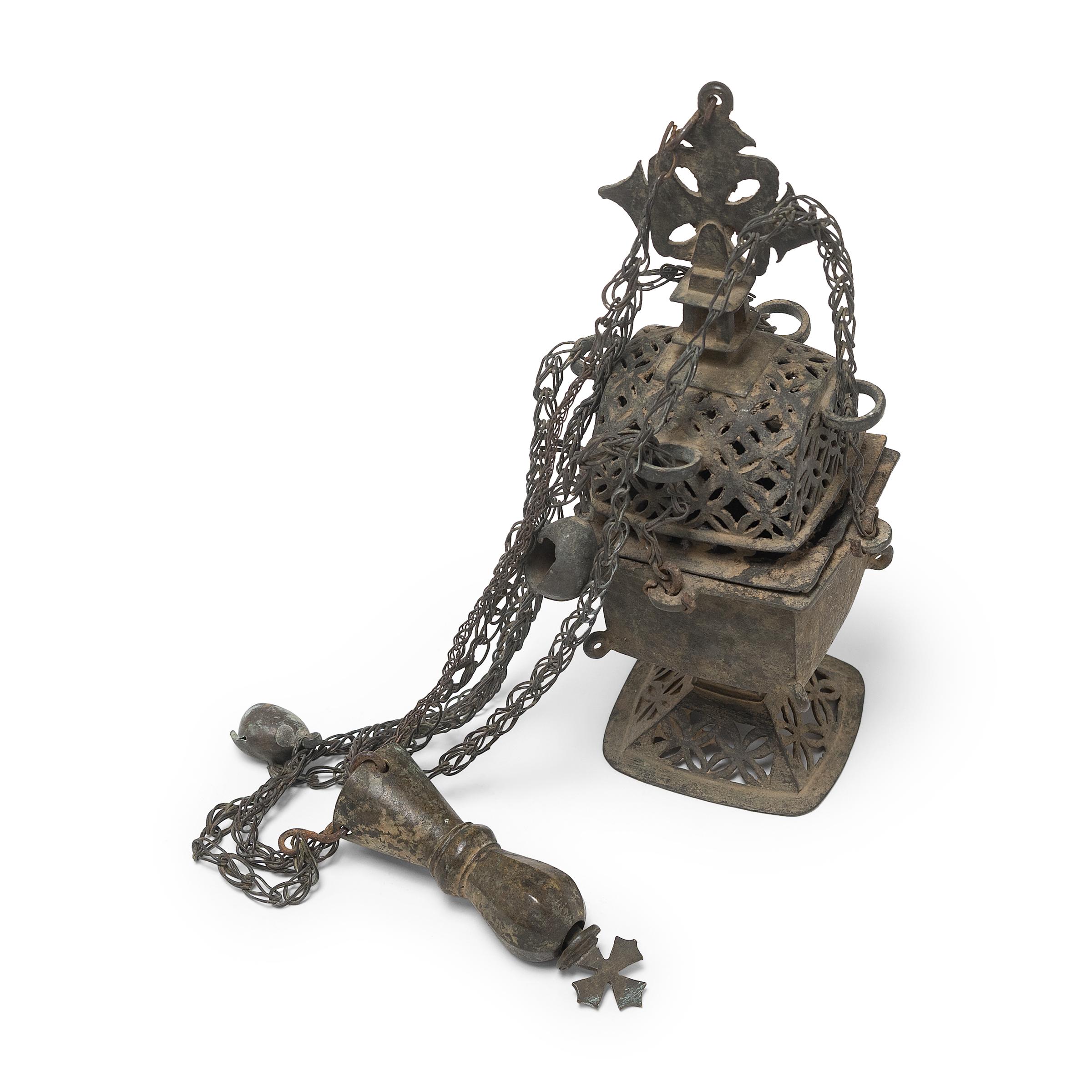 This sculptural bronze object is a 19th-century liturgical censer, or thurible, used for guided prayer and ritual ceremony within the Coptic Orthodox Church. Blessed by the Priest prior to use, the censer was lit with incense such as frankincense,