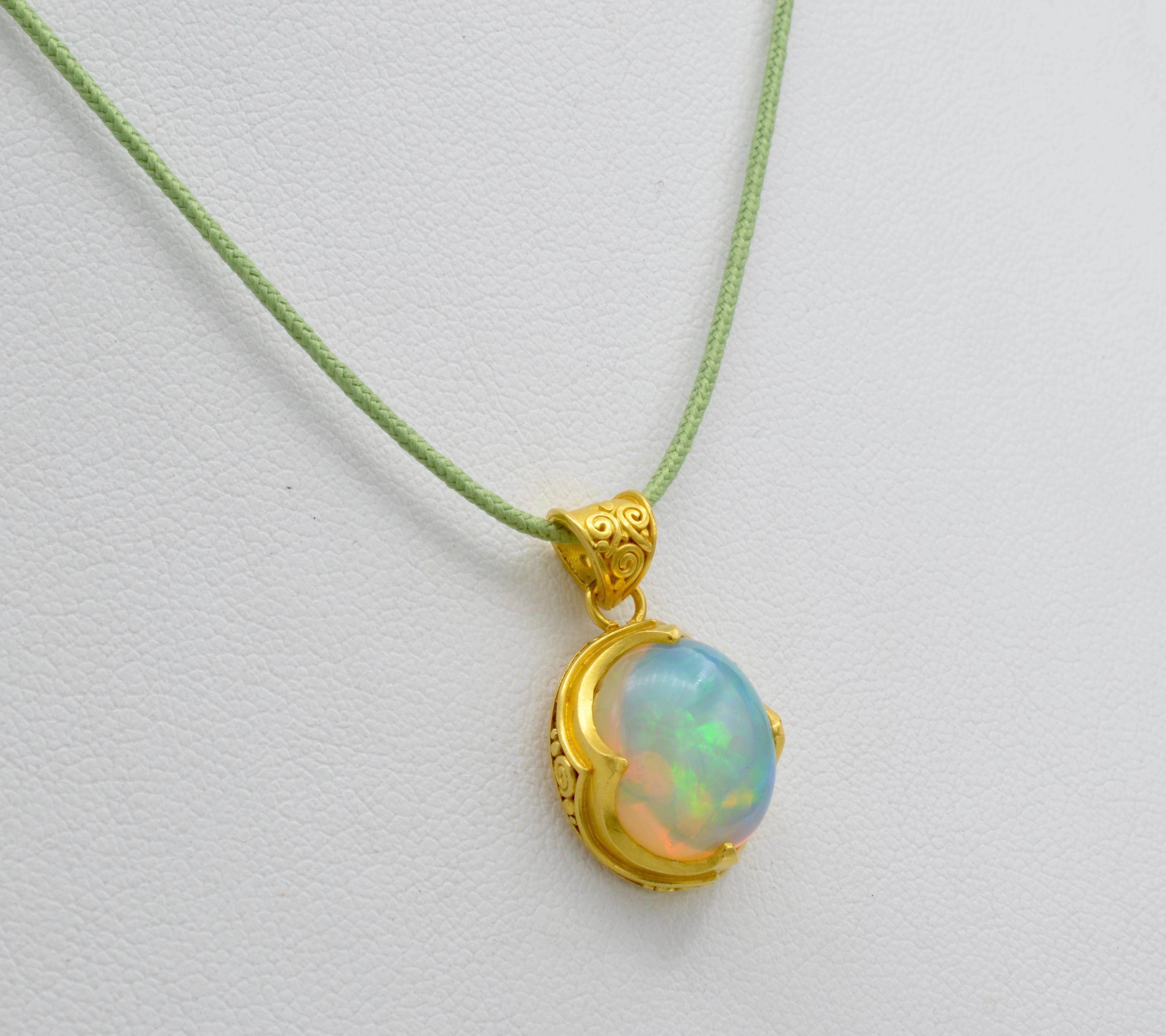 This yummy opal is vibrant in rainbow colors and brilliant light. The opal is aprox 5.5 ct and is surrounded by  a 22k gold bezel to offset the dazzle of this amazing stone. The pendant is send on a cotton cord and can be put on a chain of your