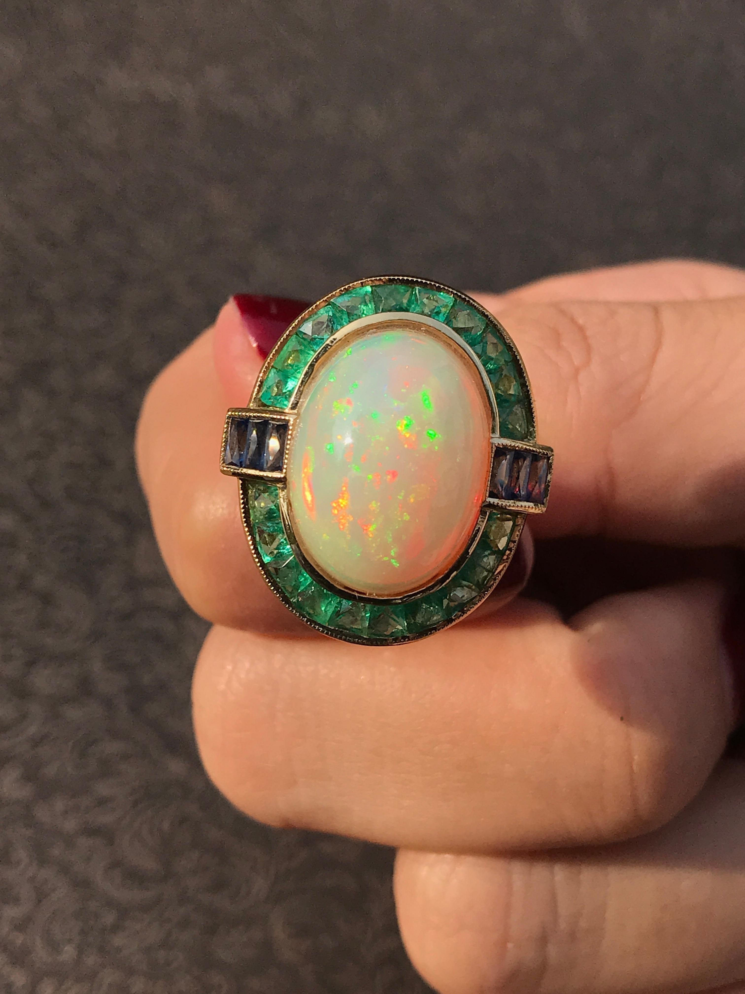 Cette bague de cocktail vibrante est ornée d'une opale éthiopienne fascinante au centre, qui rayonne d'un jeu de couleurs à chaque mouvement. L'opale est magnifiquement encadrée par de riches émeraudes de taille française, ajoutant un contraste