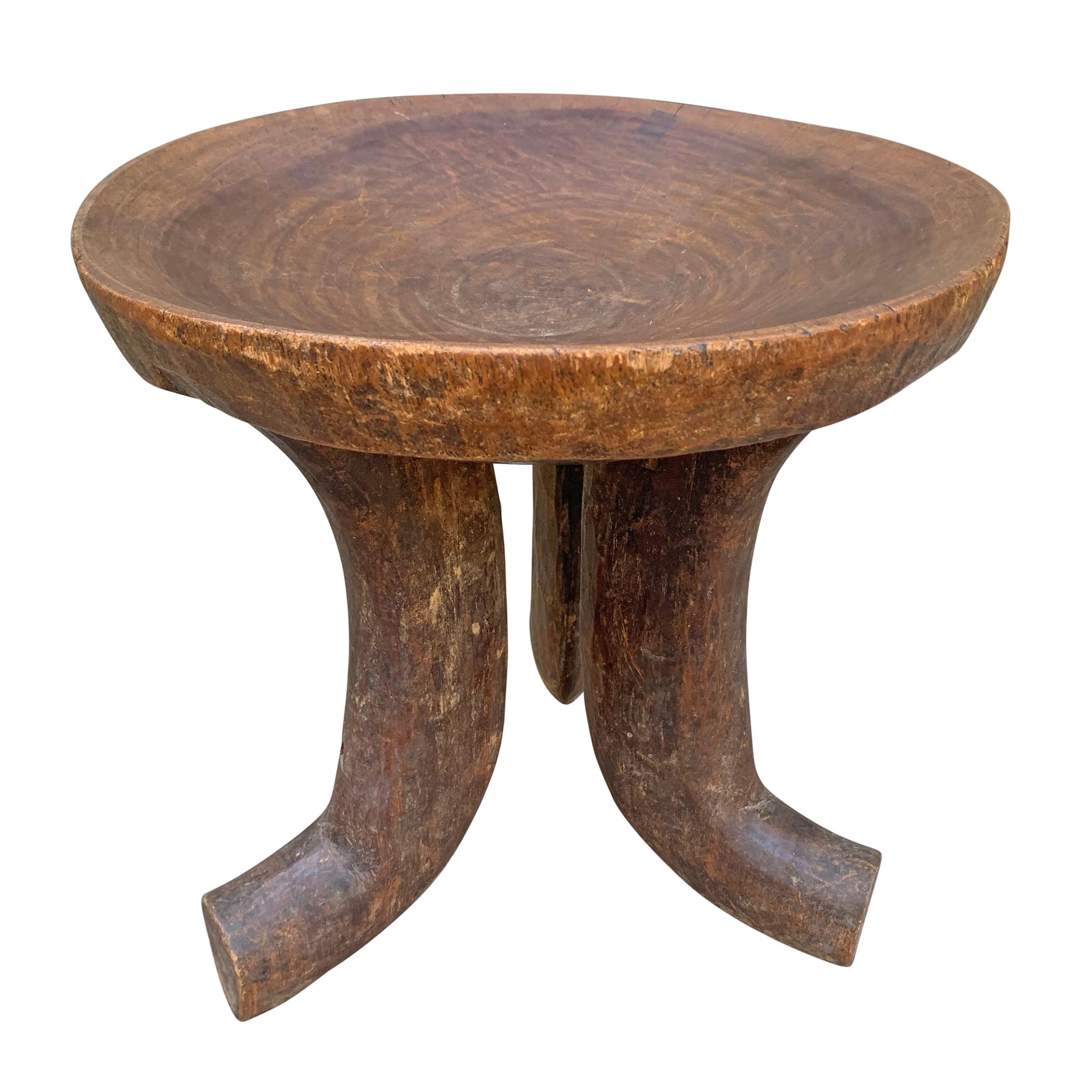 A wonderfully sculptural early 20th century Ethiopian stool carved of one piece of wood showing a hand carved texture, with three curved legs supporting a convex bowl-form seat with a beautiful patina.
