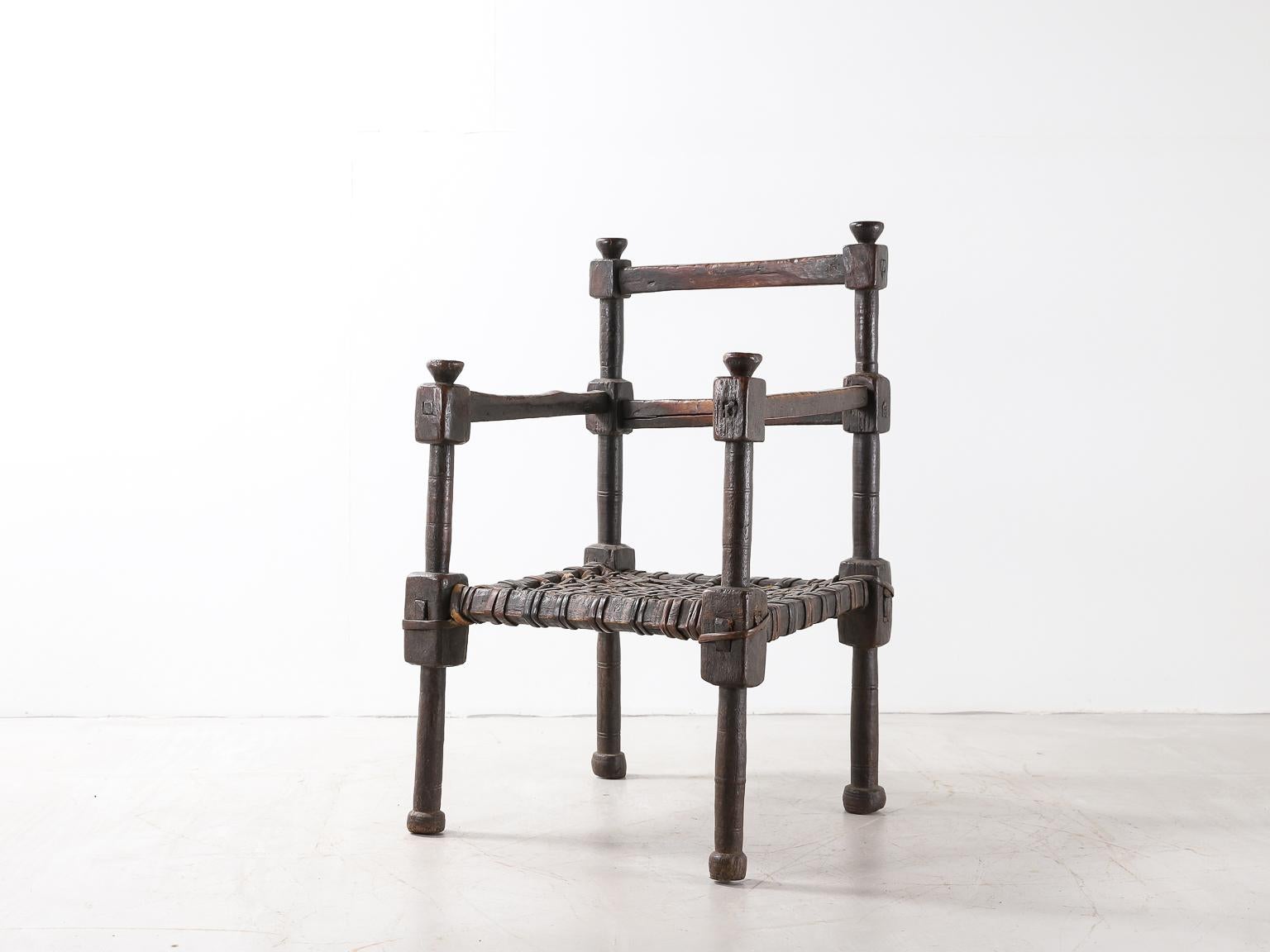 An Ethiopian chair in hand carved wood with rich patina, with woven leather seat.