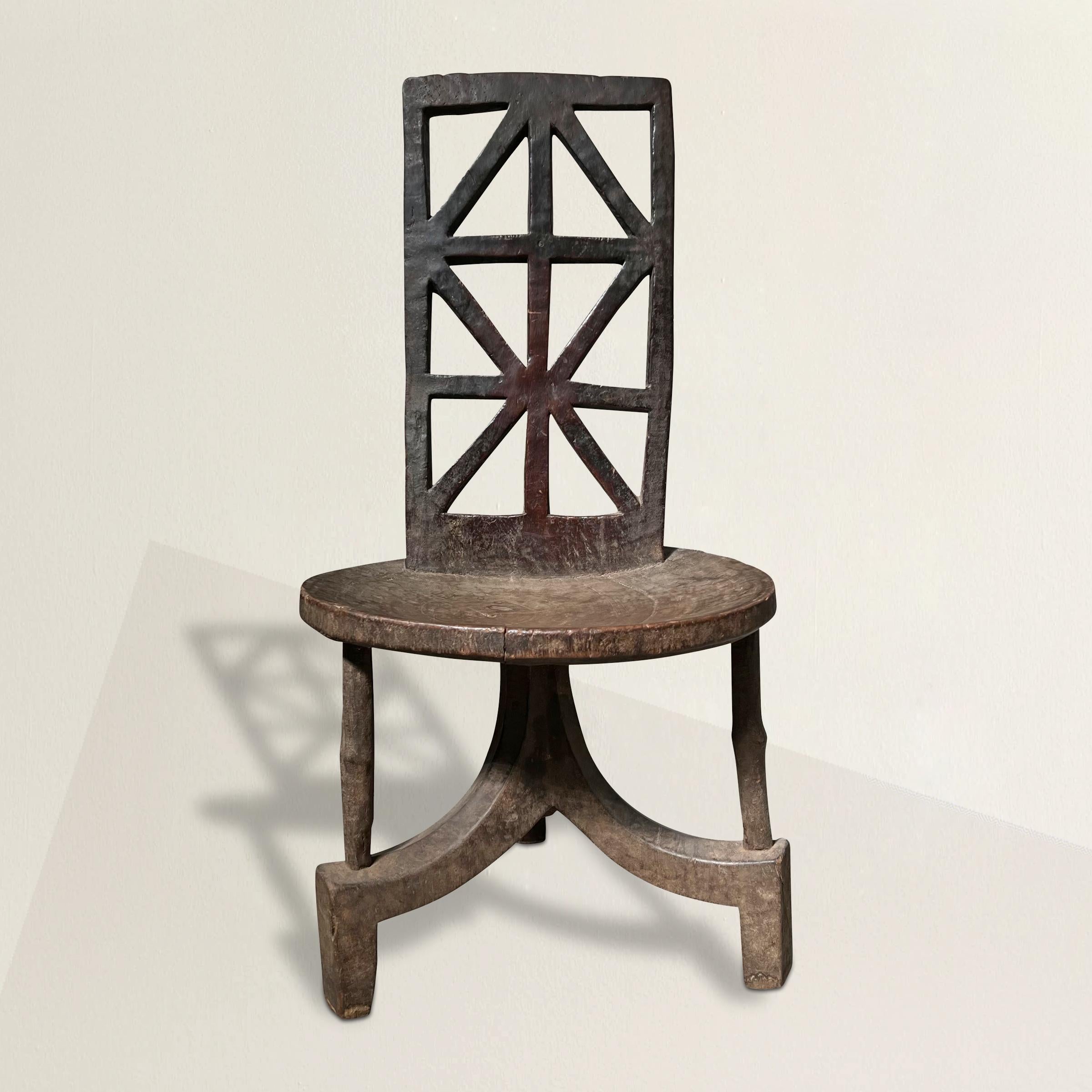 A remarkable and covetable example of a Jimma/Gurage People's Walga chair from the Omo River Region, Ethiopia. With its geometric patterned back support, round concave seat, and tripod legs, this chair has been carved from a single piece of wood and