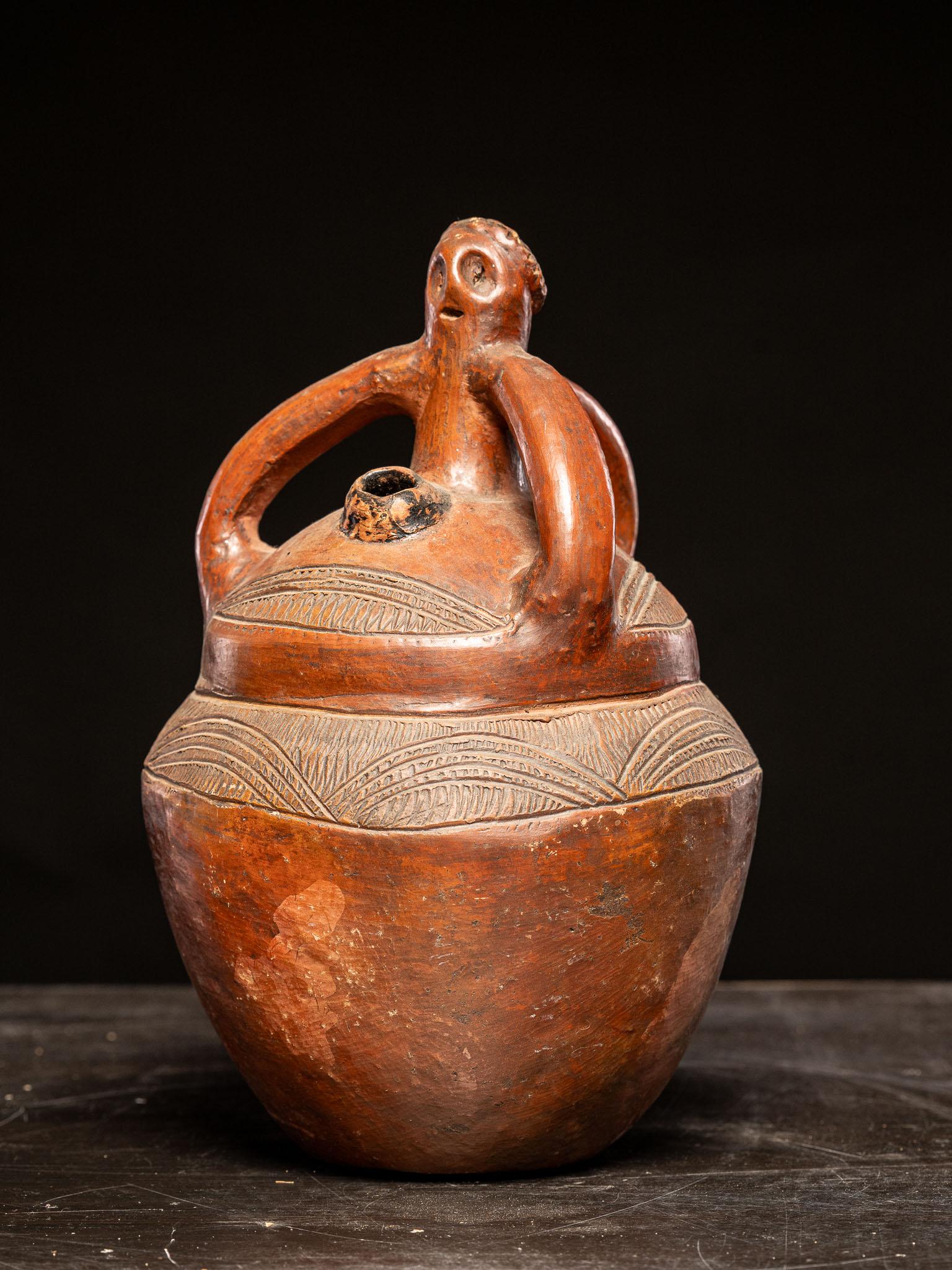 This vessel exemplifies the anthropomorphic style, incorporating distinct human-like features into its design. Most notably, the upper portion of the vessel includes a stylized human figure with a head and outstretched arms, seamlessly integrated