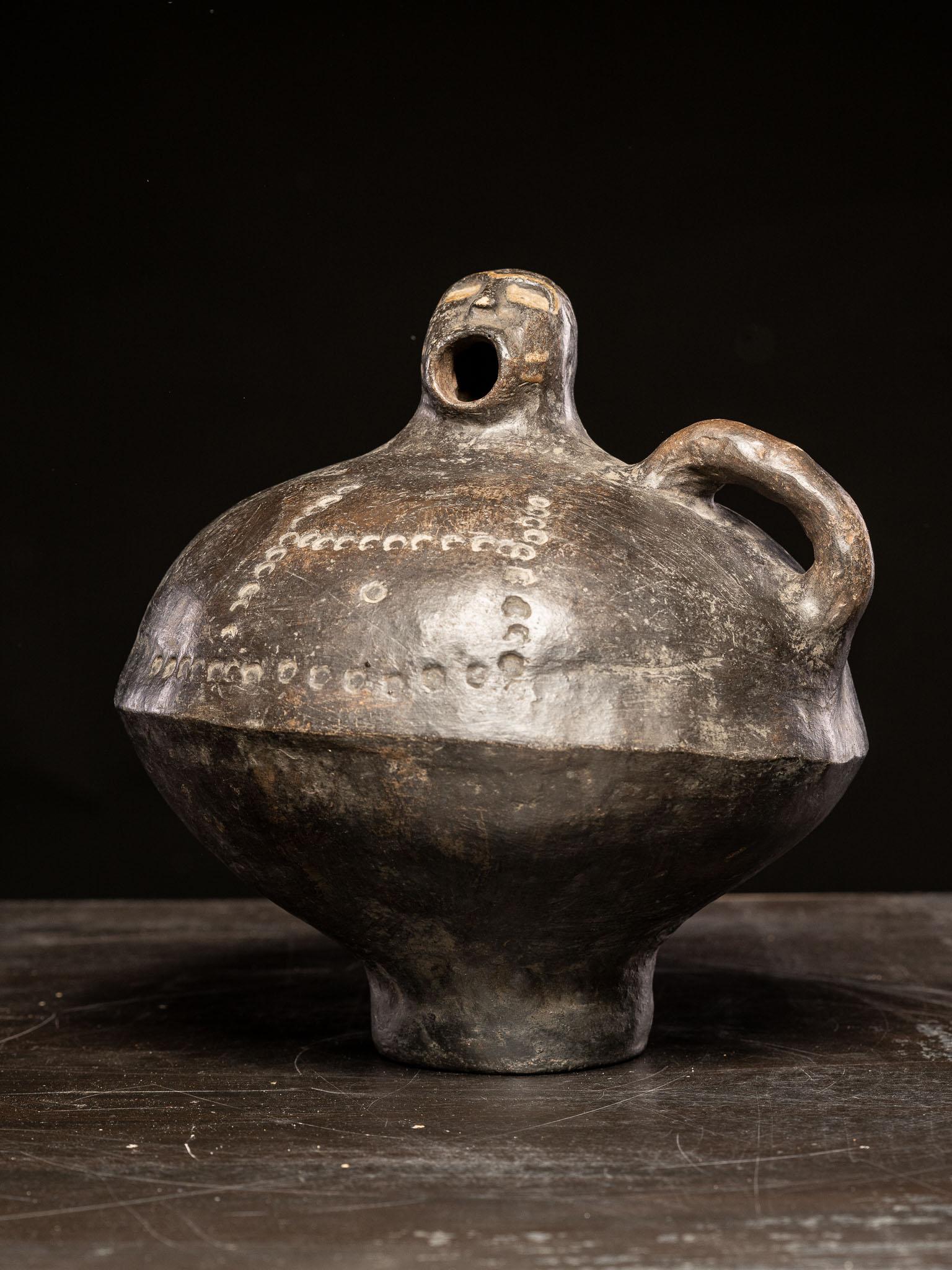 This vessel vividly illustrates anthropomorphic design through its bold depiction of a human-like figure. The spout is sculpted as an open-mouthed face, complete with stylized eyes and a rounded head, giving the impression of a vocal or expressive