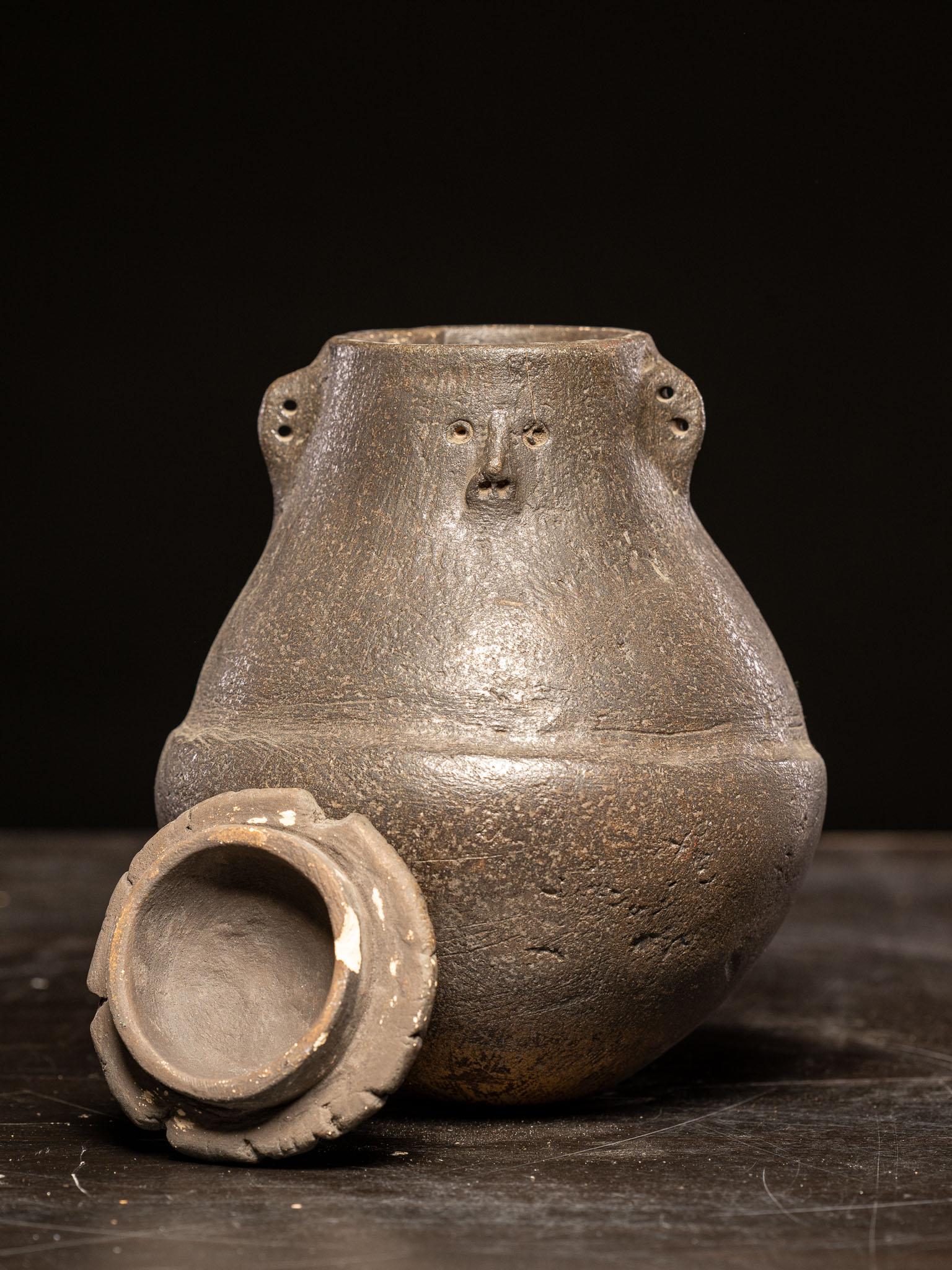 This vessel demonstrates anthropomorphic qualities through the subtle inclusion of human-like features. The rounded form evokes the shape of a torso or belly, while the small facial elements—eyes, nose, and mouth—are clearly modeled on the upper