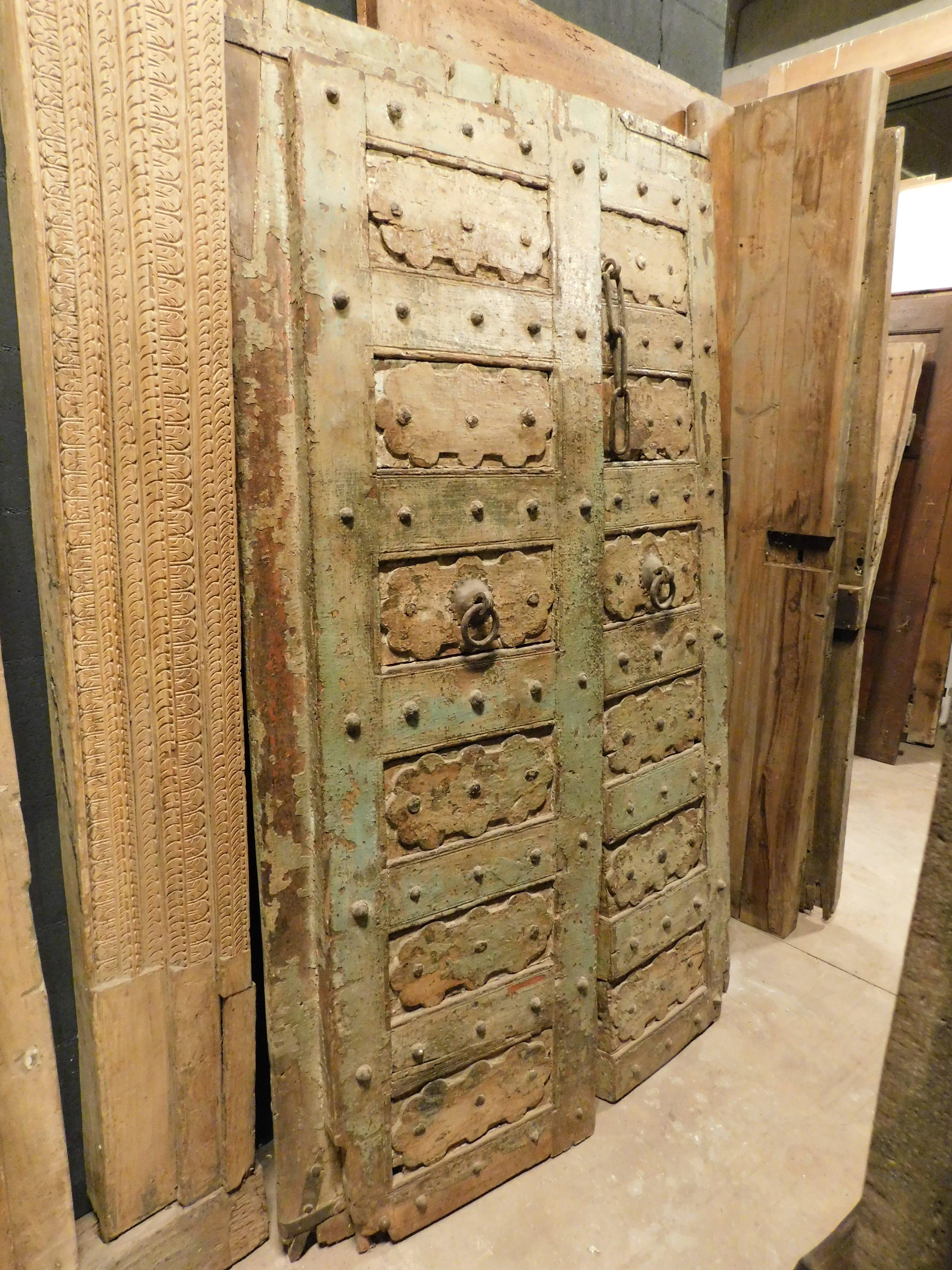 Ancient old entrance door, ethnic and in very heavy teak wood, very solid, green lacquered with rich sculptures, coming from a house in India, it is very powerful, with original irons (both floor and ceiling hinges, and hooks, chains for animals) .