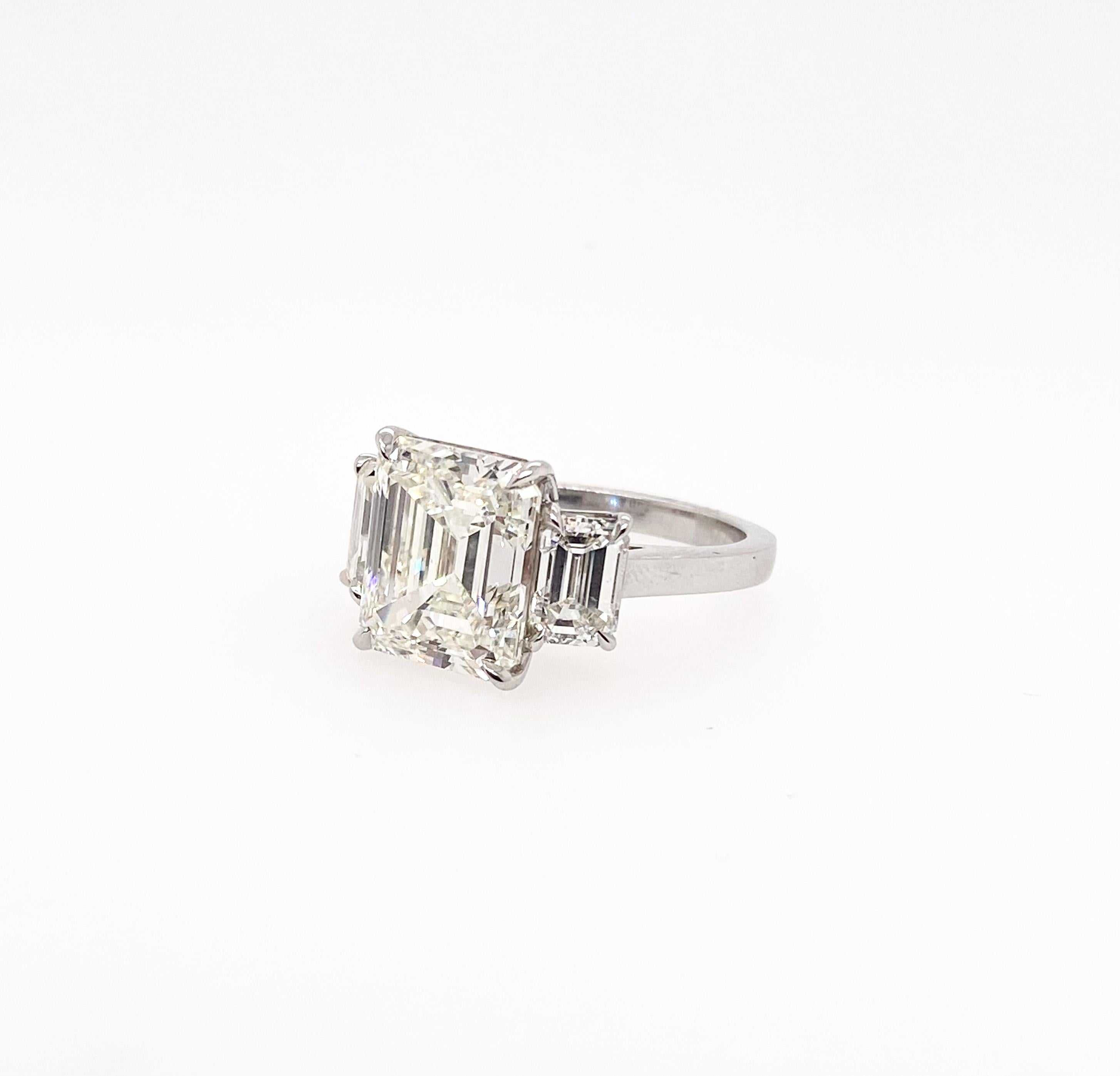 This three-stone ring is fully set with the certified Emerald cut diamonds. The 5.82carat with IGI Certificate emerald cut diamond in the center is perfectly accentuated with two beautifully certified emerald cut diamonds mounted on the side