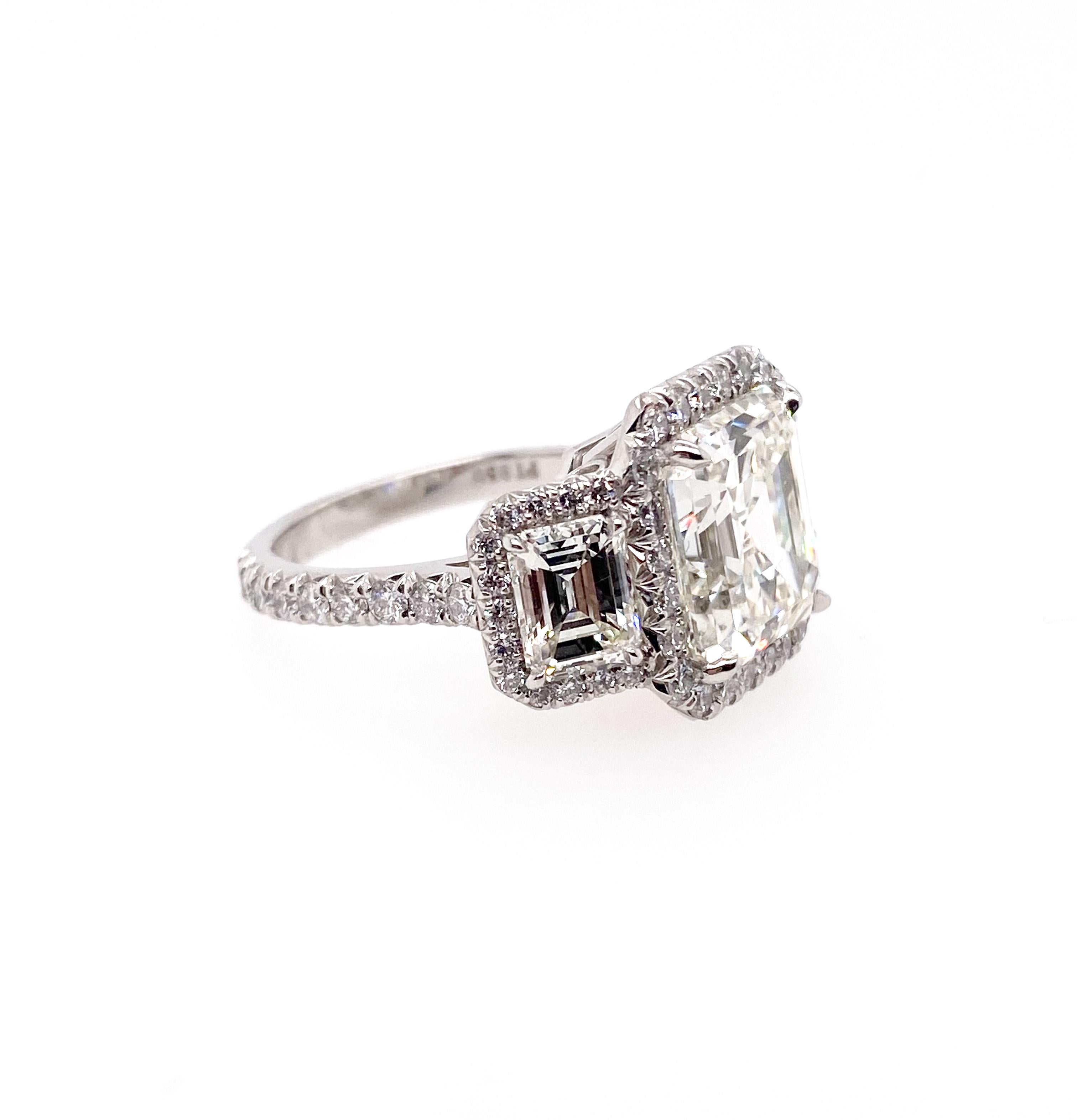Schöner GIA-zertifizierter Diamant mit 6,13 Karat im Asscher-Schliff, montiert in einem Platinring als Mittelstein. Er ist mit zwei GIA-zertifizierten Diamanten im Smaragdschliff von jeweils 0,90 Karat besetzt. Darüber hinaus rahmten die runden