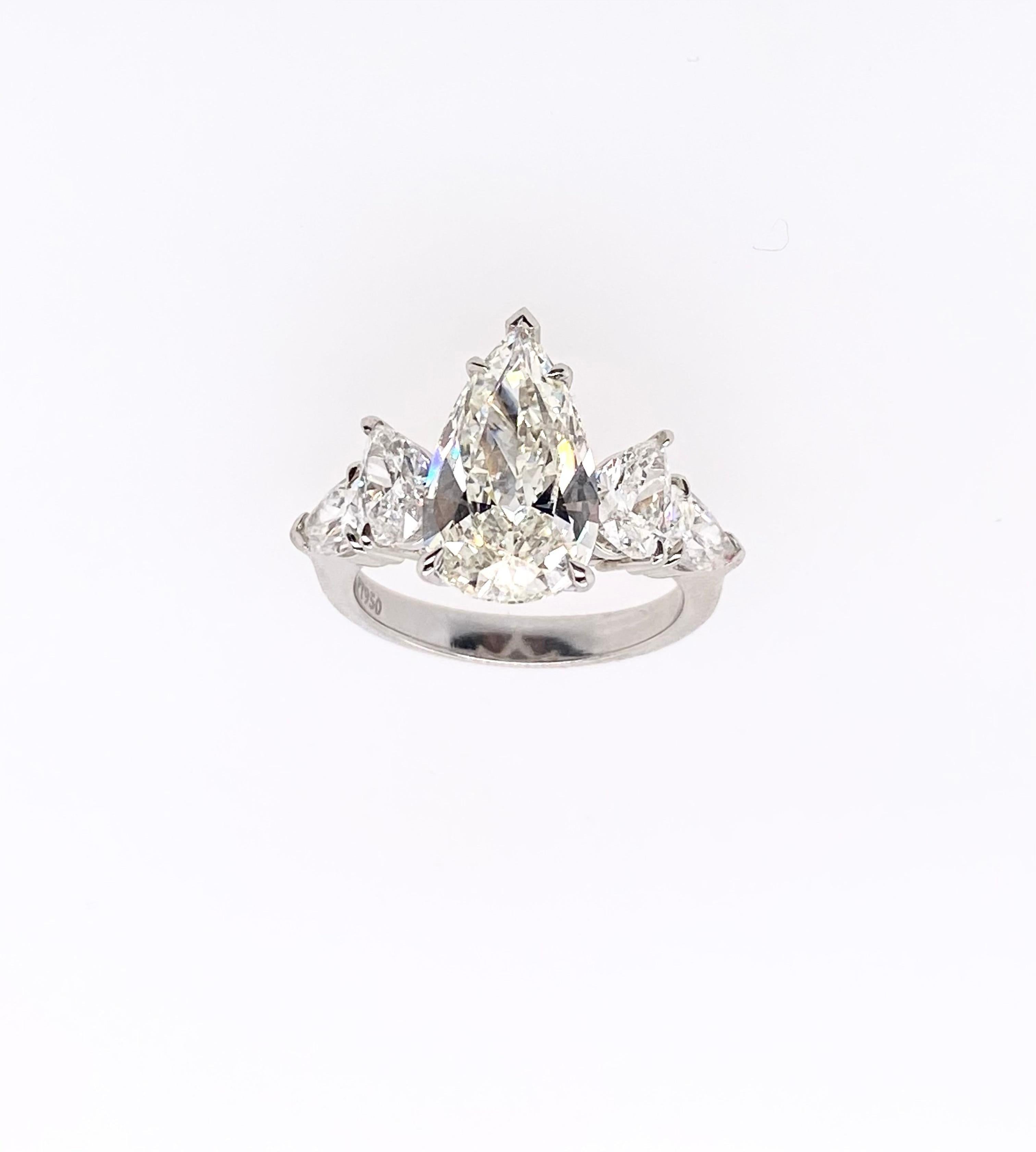 GIA Certified 3.23 carat pear shape diamond is perfectly accentuated with another two beautifully pear shape diamonds per side (as total four pear shape diamonds for both sides) mounted respectively in platinum ring. This stylish four-stone ring