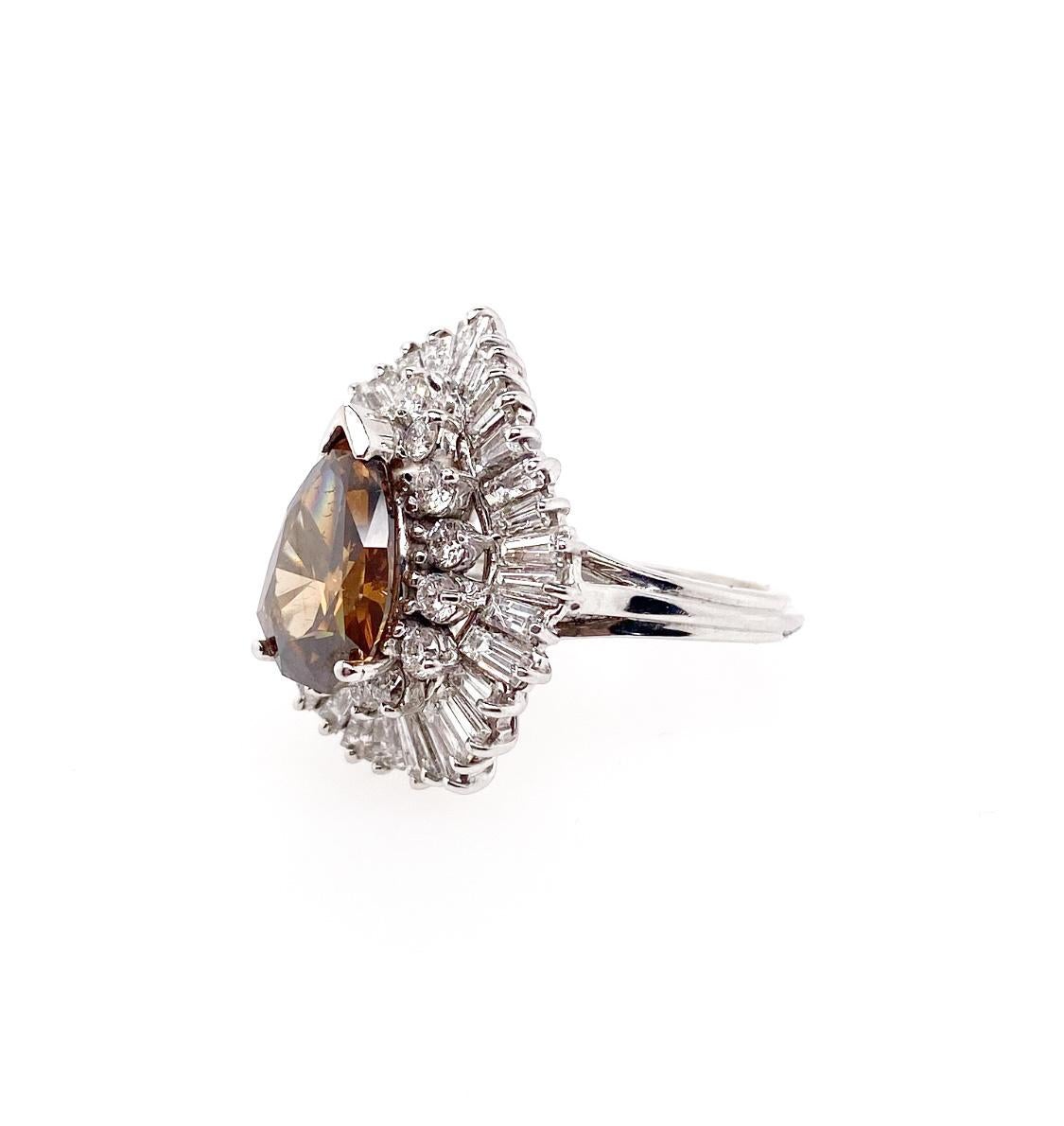 Le diamant Fancy Brown Shield de 3,20 carats certifié par le GIA est monté comme diamant central de la bague. Ce diamant rare, unique et fabuleux, est entouré de diamants ronds et baguettes brillants dans un style ballerine. Cette bague est