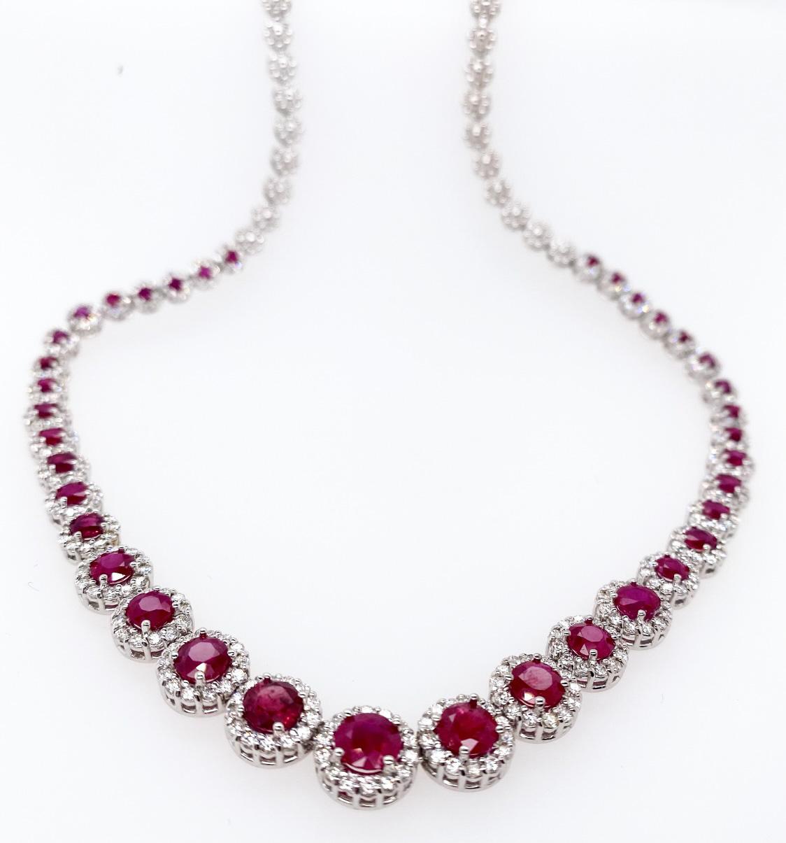 Ce magnifique collier présente un rubis rougeâtre de taille ronde rehaussé d'un halo de diamants ronds de taille brillante sertis dans de l'or blanc 18K. Le collier est composé de trente-sept rubis gradués avec des grappes de diamants. Ce magnifique