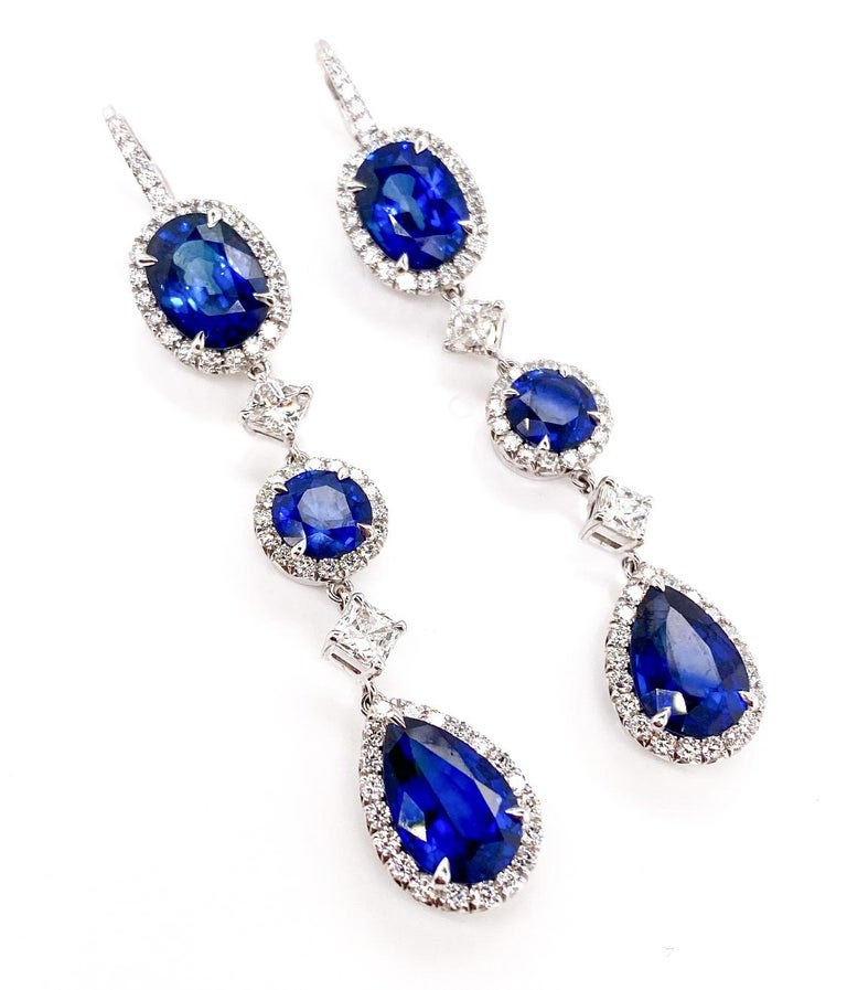 This contemporary earrings gives a strong impression look. The top quality six deep blue sapphires, shaped in Oval, Brilliant Round and Pear, are surrounded by a halo of round brilliant-cut diamonds set in 18K white gold. Between the