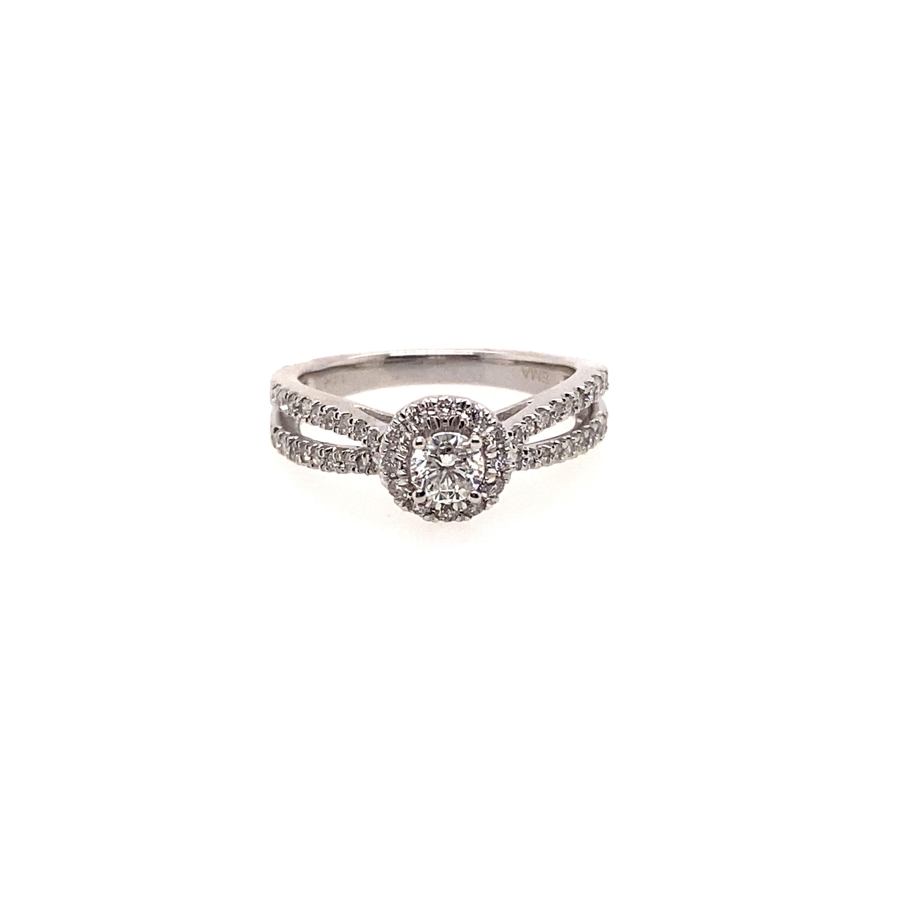 Perfect for the woman who loves a classic round diamond ring and who likes a little adventure in the shank which is designed as 14K white gold double loop ring. Center stone 0.35 carat diamond is surrounded by a halo of round diamonds and the double