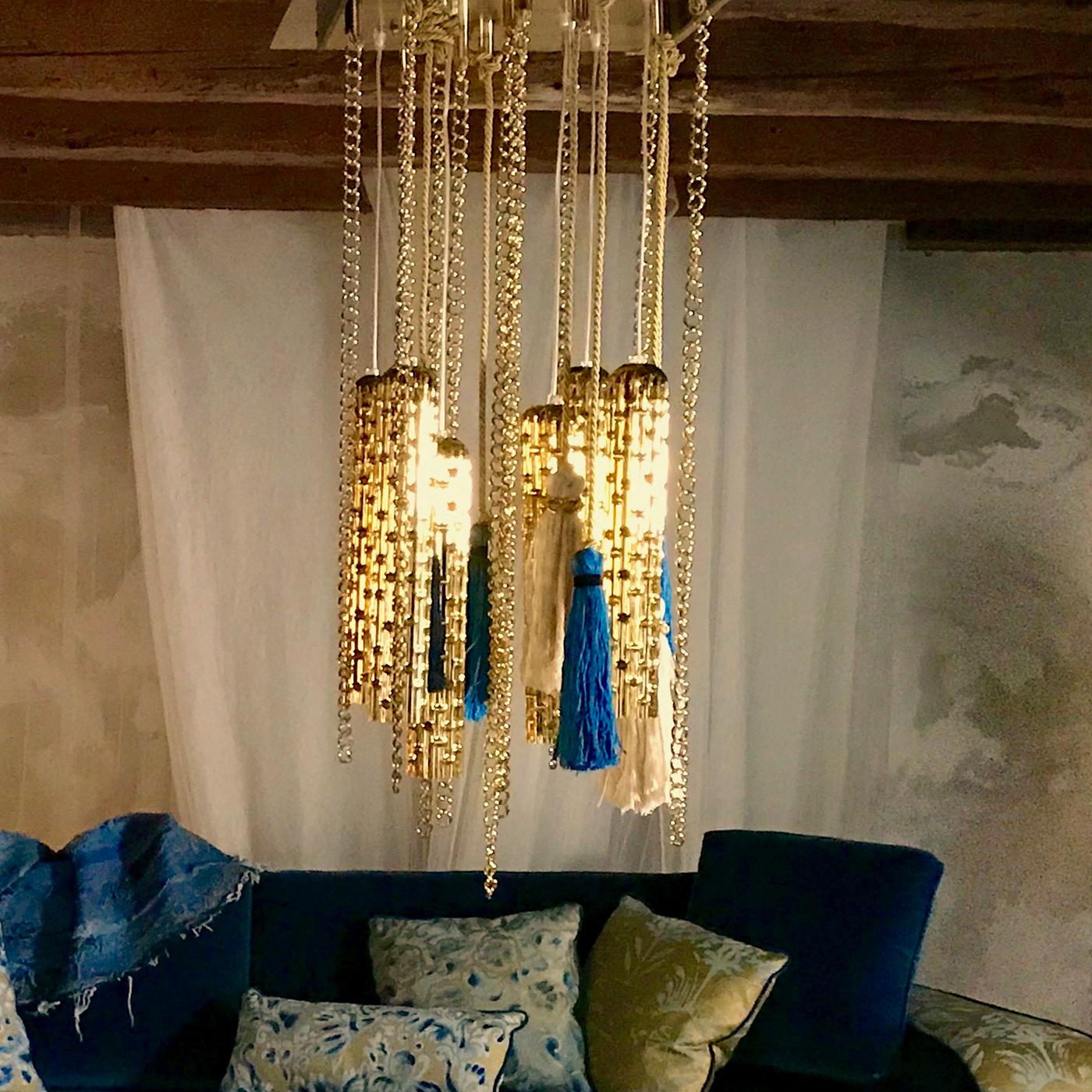 Designed by Slow+Fashion+Design and realized by Venetian artisans, this unique chandelier revisits the classic Murano glass style with a modern and unconventional twist. White, cobalt and gold silk tassels, golden chains, and elaborately decorated
